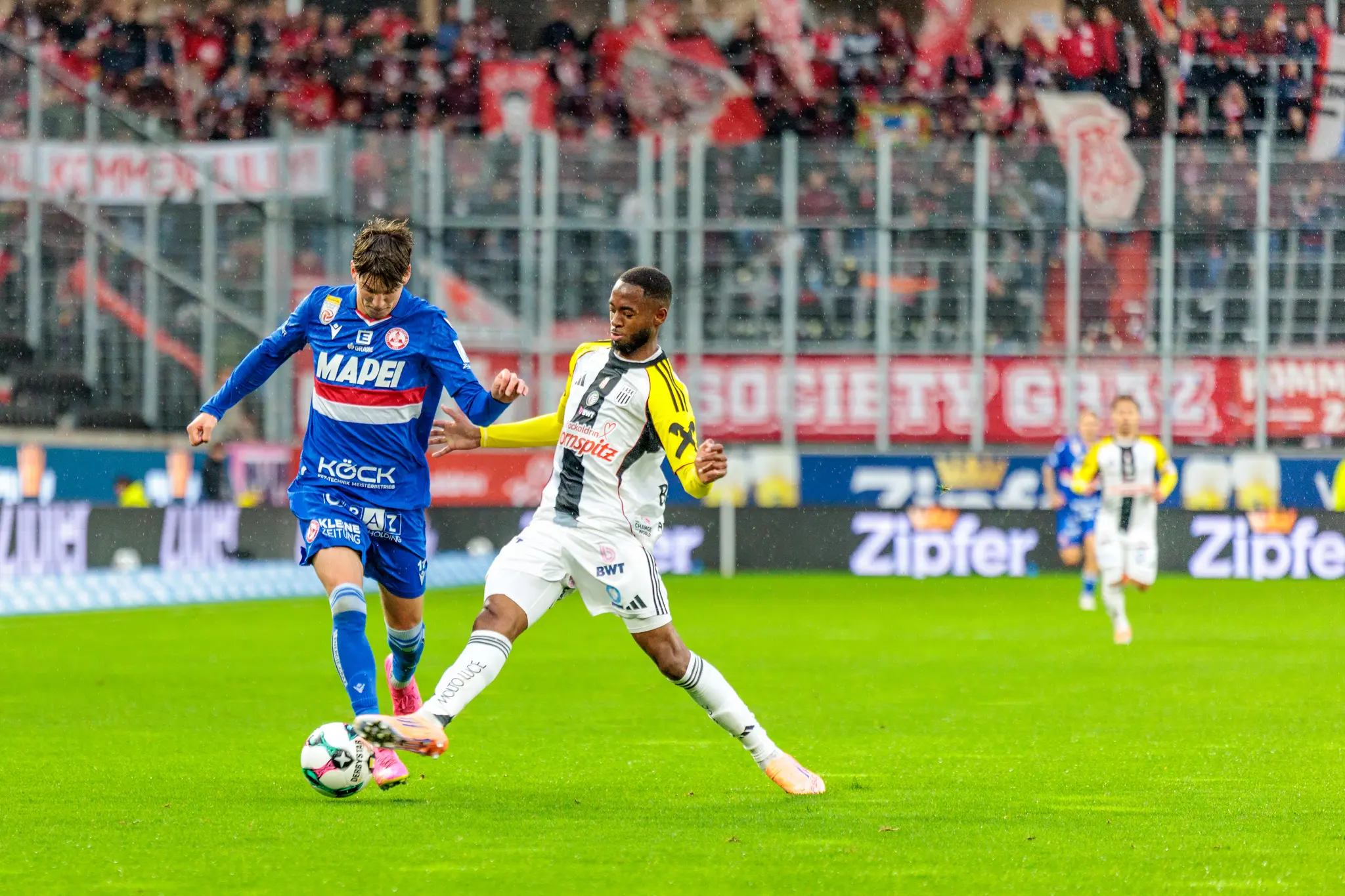 GAK-Spieler Tio Cipot führt den Ball am Fuß und wird im intensiven Zweikampf von einem Verteidiger des LASK attackiert