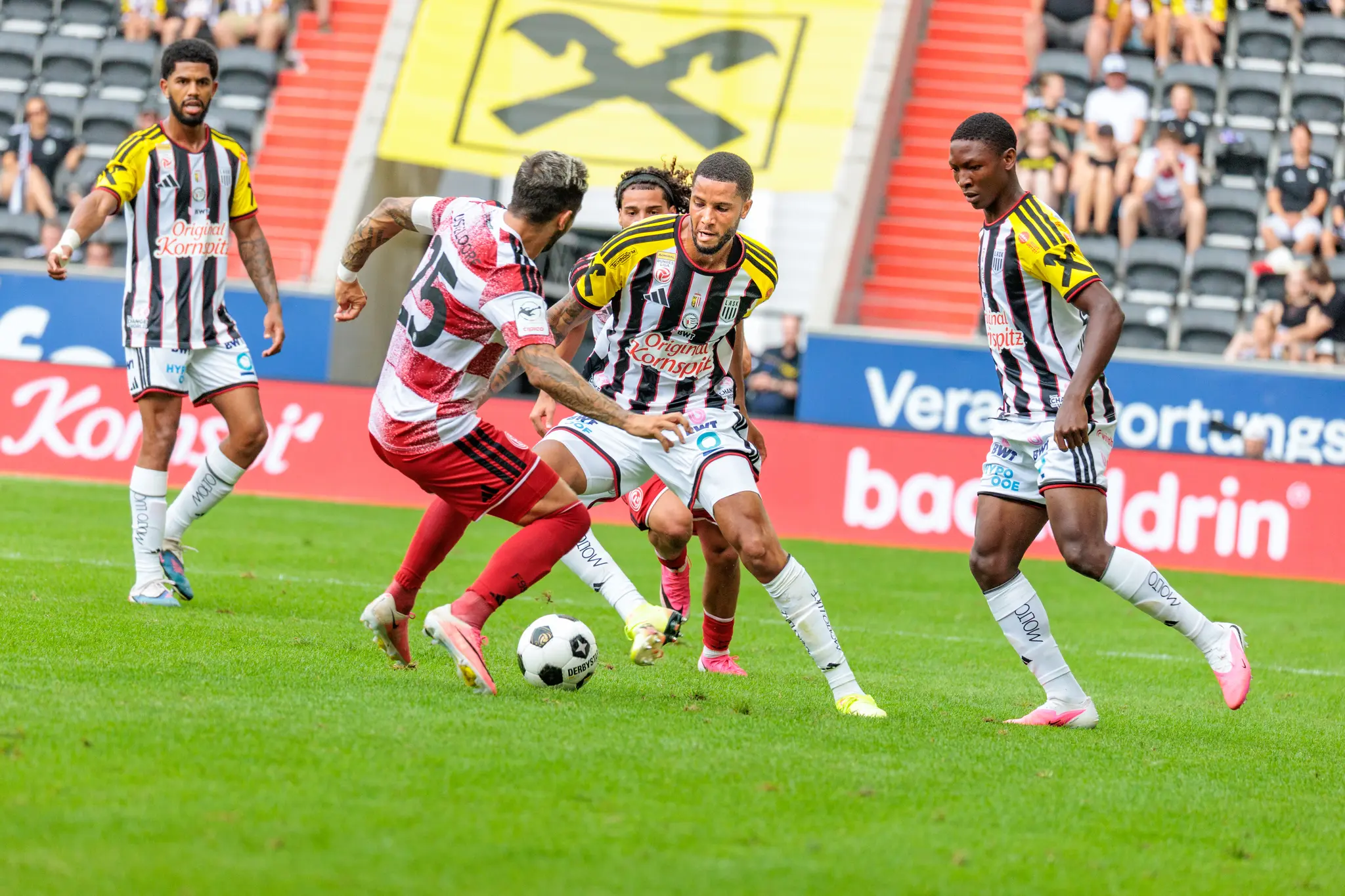 LASK-Spieler im intensiven Zweikampf mit Düsseldorfer Spieler Nummer 25 um den Ball, kurz vor dem Ende der Partie.