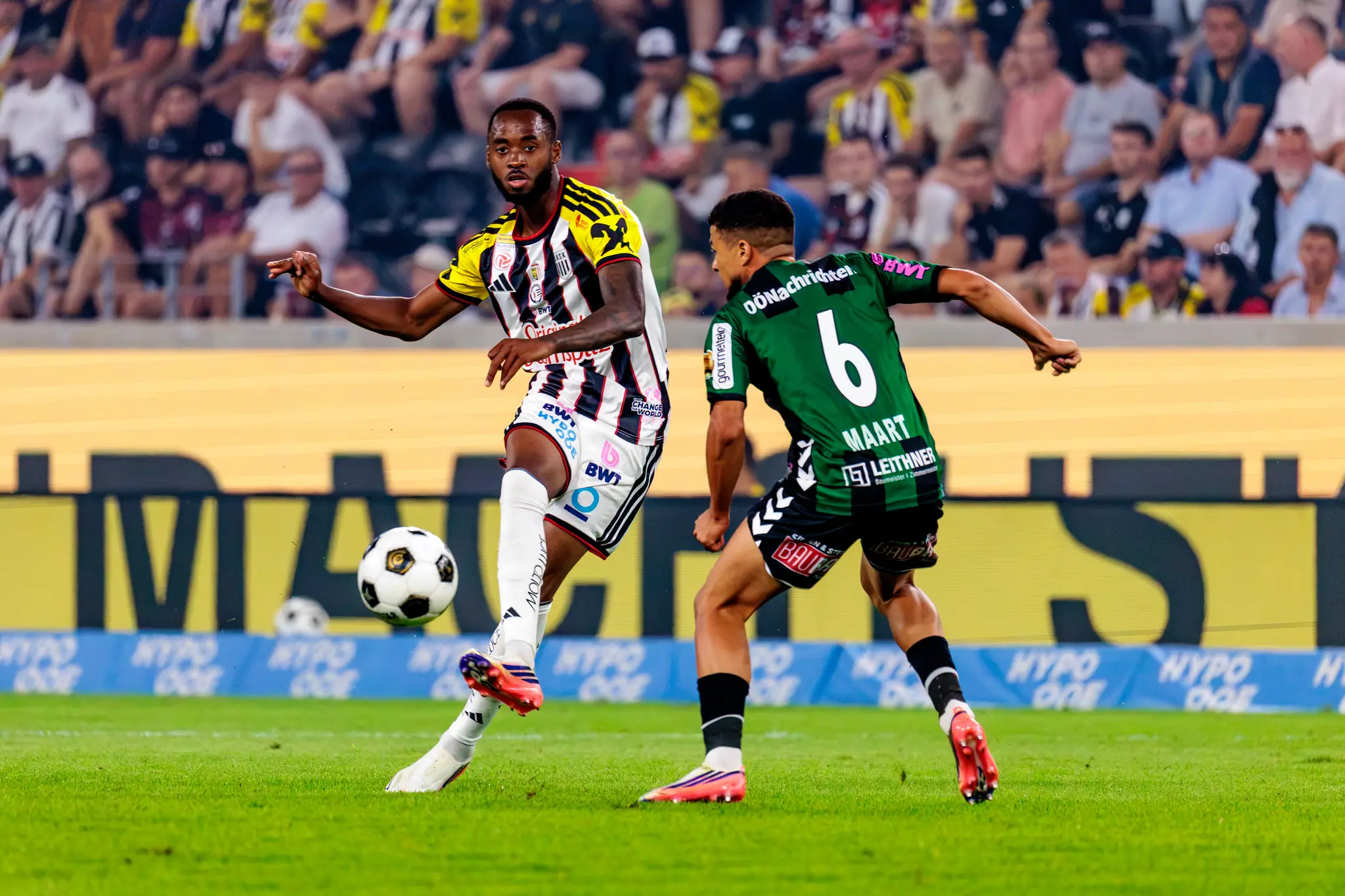 Ein LASK-Spieler dribbelt, SV-Ried-Spieler Maart (Nr. 6) stellt den Laufweg zu