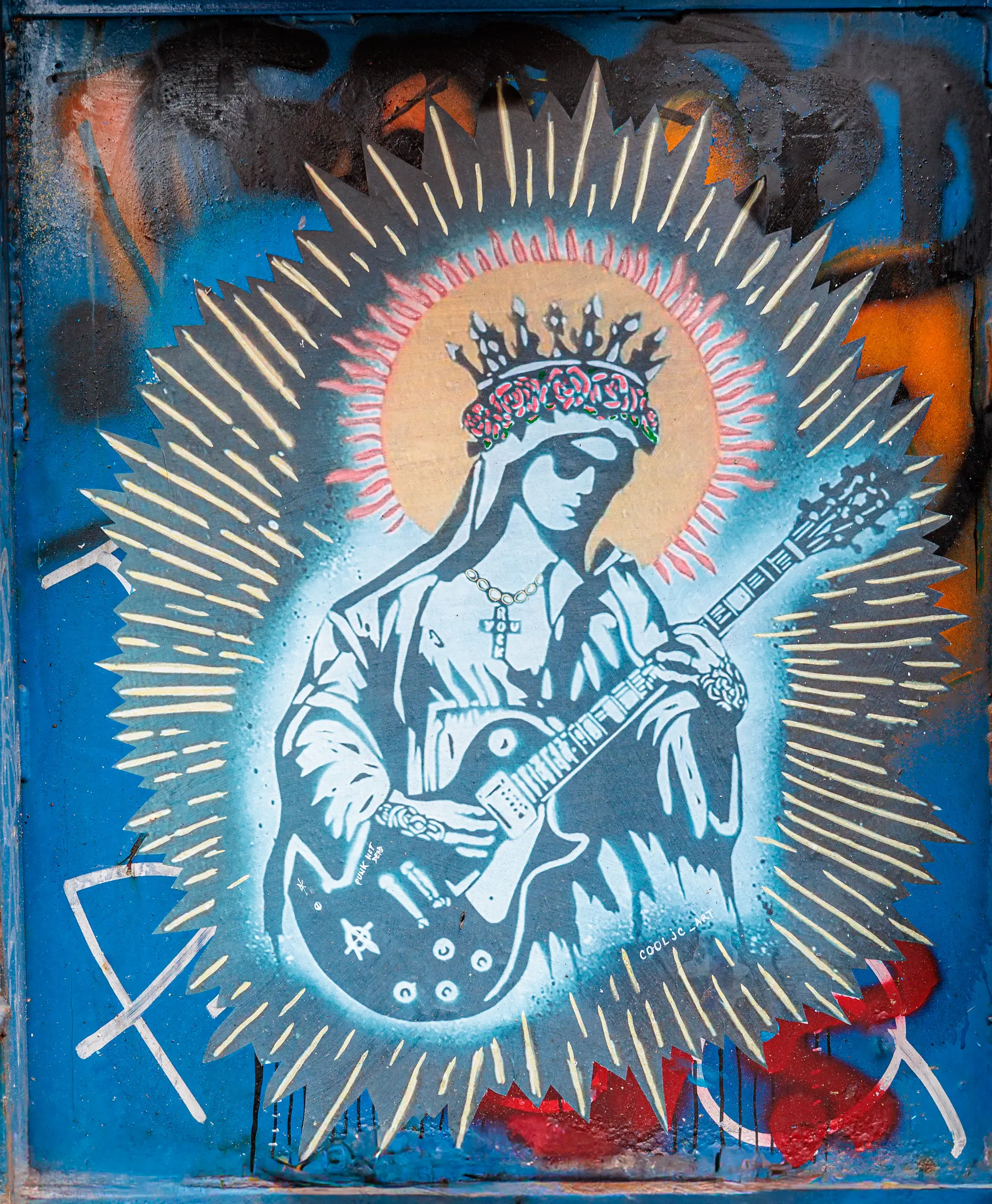 Ein rebellisches Wandgemälde in Amsterdam zeigt eine gekrönte Madonna mit E-Gitarre, umgeben von einem leuchtenden Strahlenkranz auf einer blauen Wand