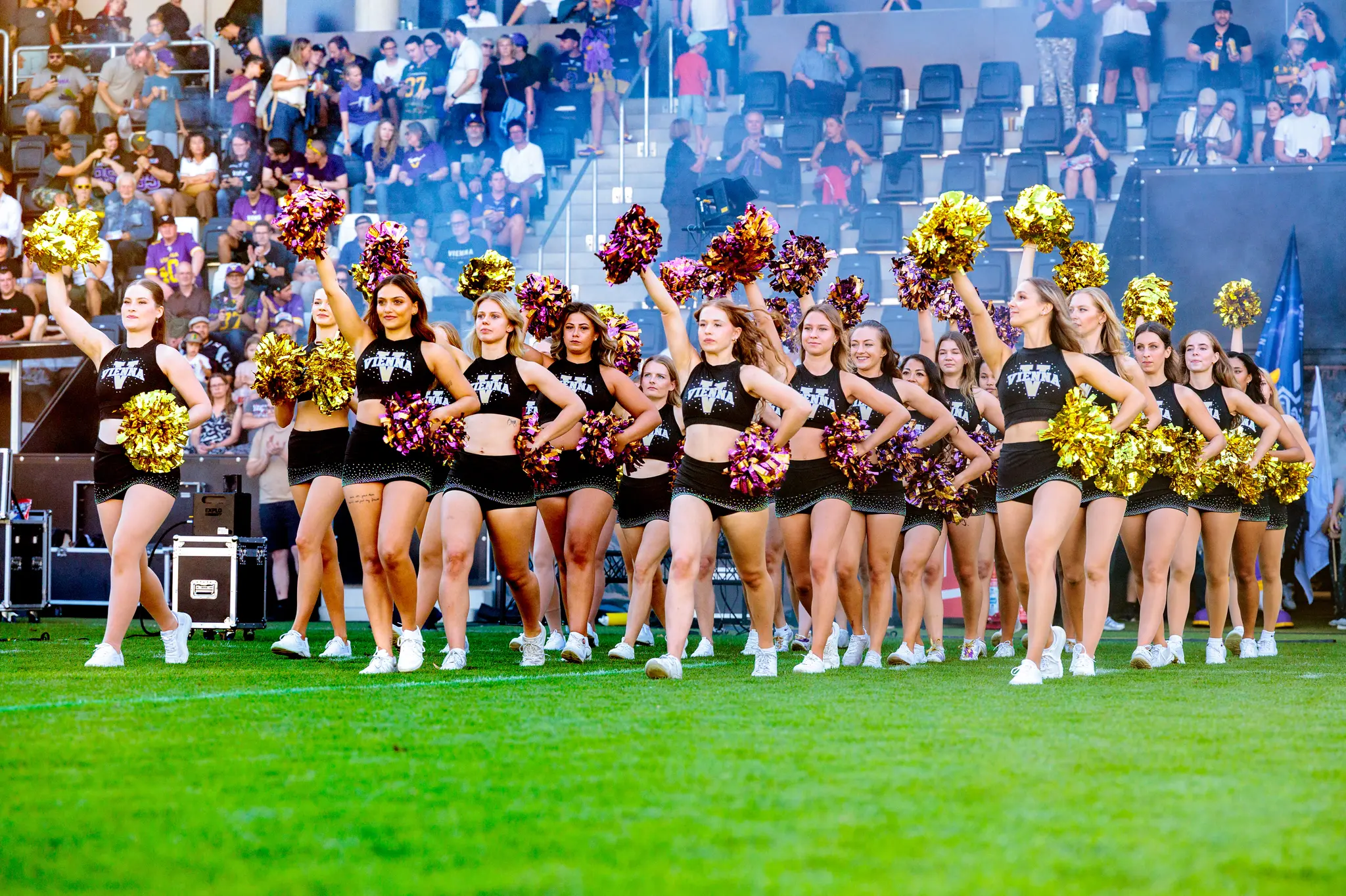 Einzug beider Teams im Vorabendlicht: Vienna Vikings und Firenze Red Lions betreten gemeinsam den Rasen, flankiert vom Vienna Vikings Spirit Squad mit violett-goldenen Pompoms.