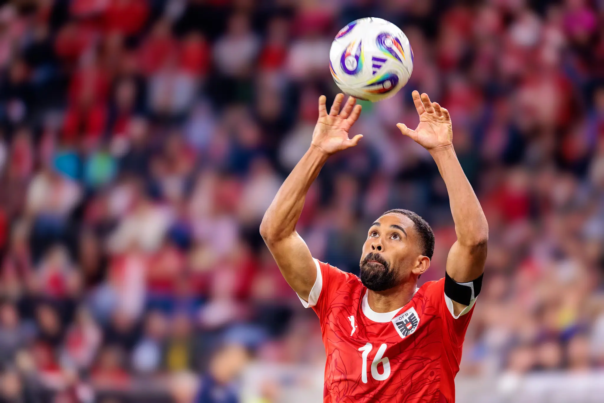 Der österreichische Fußballspieler Phillipp Mwene (Trikotnummer 16) blickt beim Ausführen eines Einwurfs konzentriert dem Fußball nach
