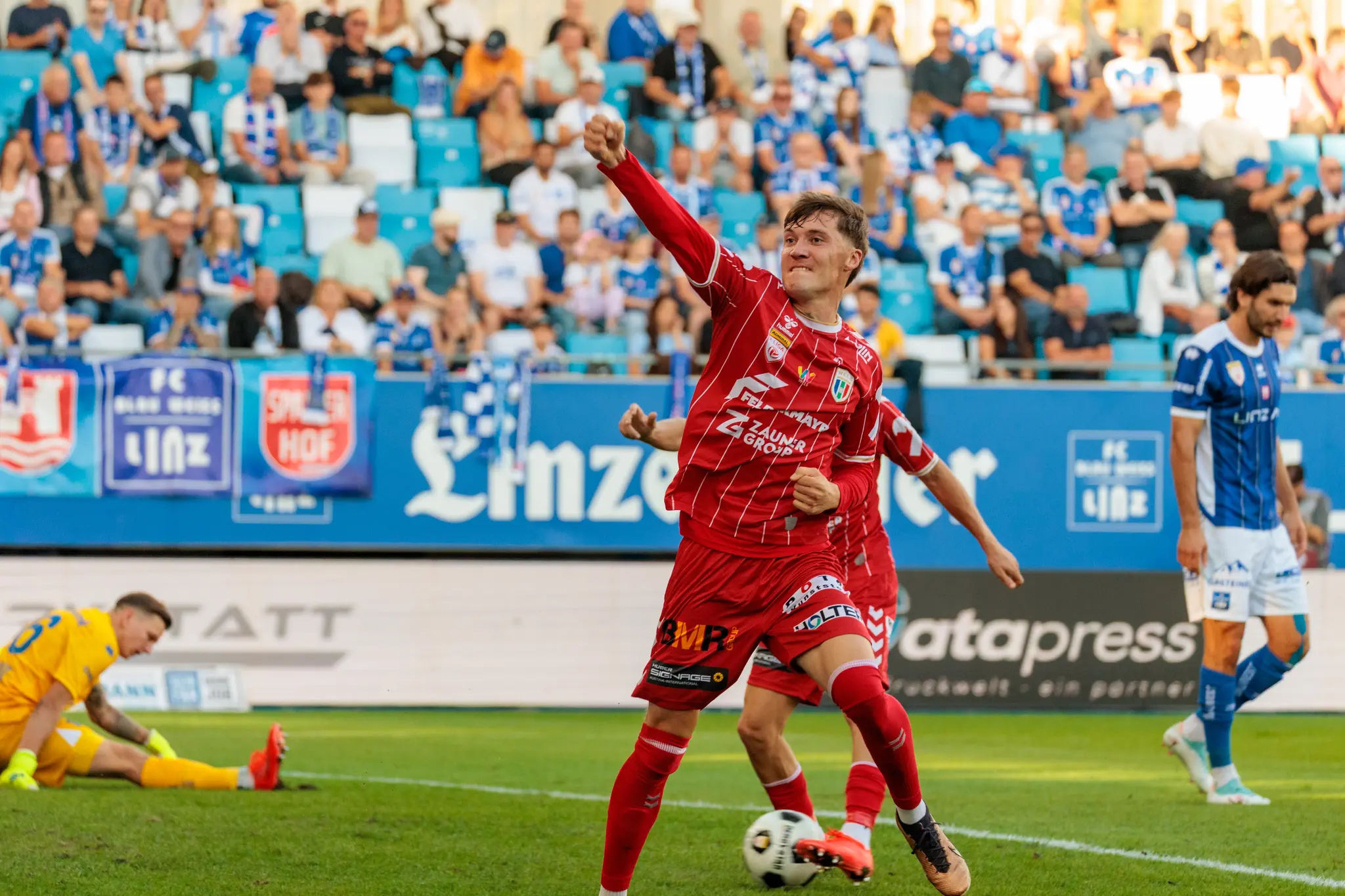 Der Welser Torschütze Sebastian Malinowski jubelt mit erhobener Faust vor der Heimtribüne, während Torhüter Christopher Giuliani im Hintergrund niedergeschlagen am Boden sitzt; weitere Welser Spieler folgen.
