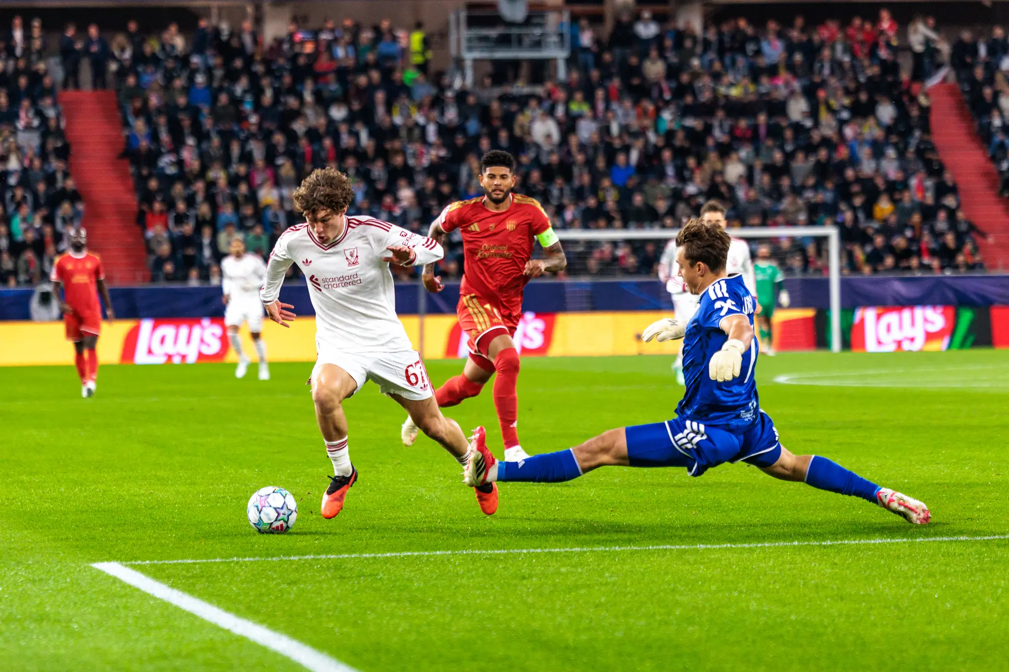 Nach seiner Grätsche rutscht LASK-Torwart Jungwirth (1) über den Rasen, Koumas (67) und ein LASK-Spieler mit Kapitänsbinde verfolgen den Ball.
