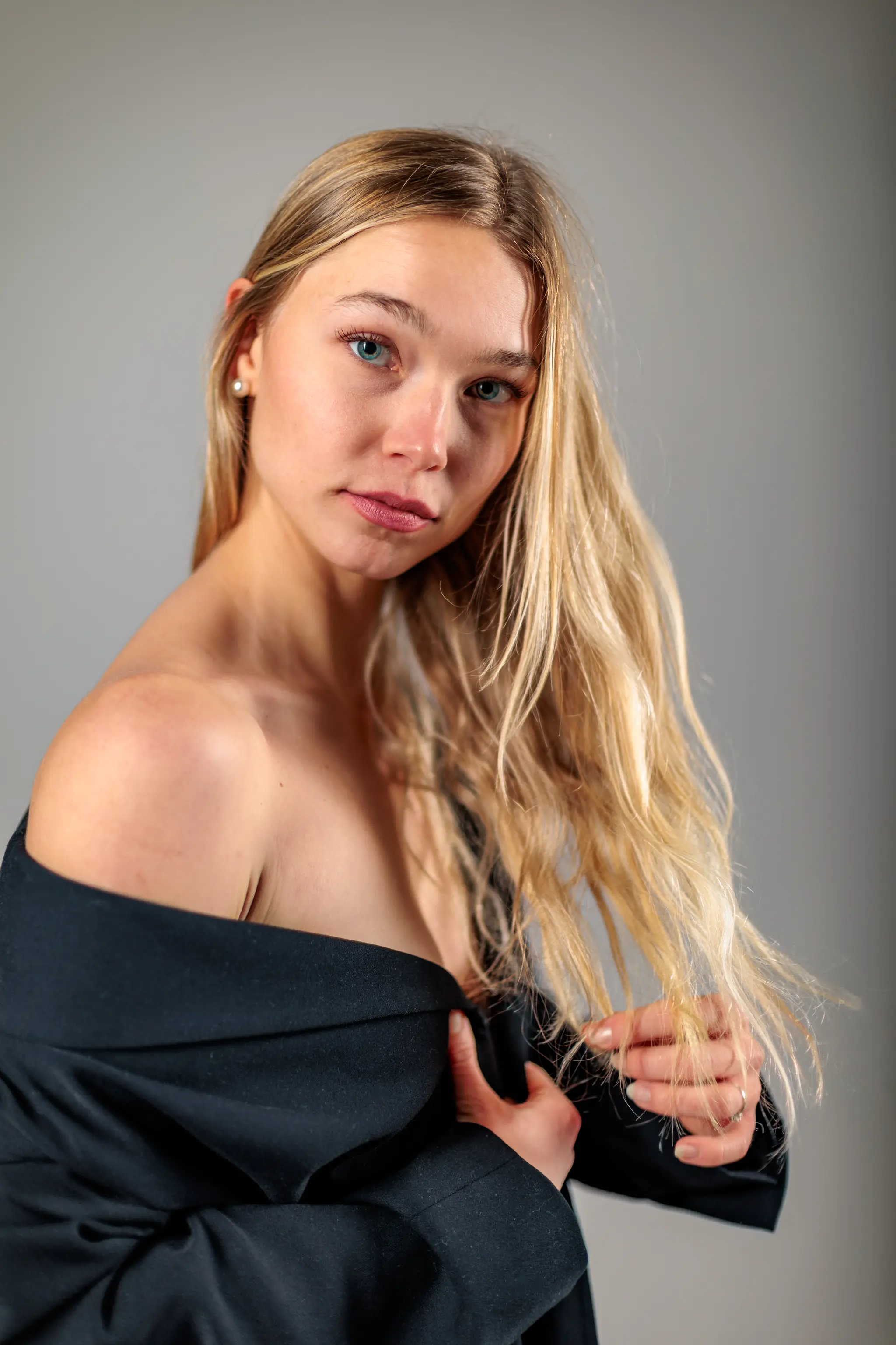 Stilvolles Porträt von Model Kathrin in einem schulterfreien schwarzen Blazer während einer professionellen Studio-Session