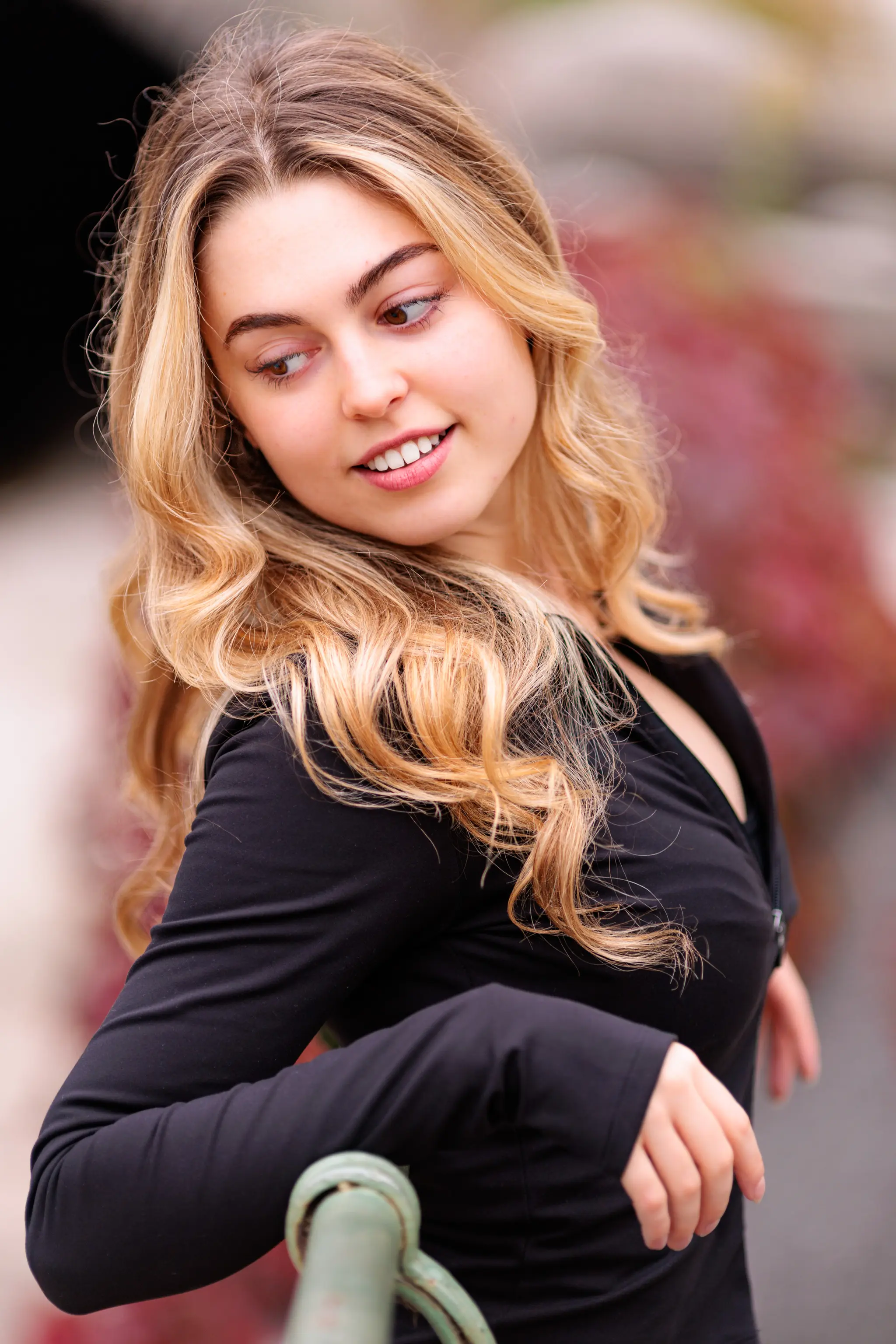 Model Valentina mit langen, blonden Locken blickt bei einem Porträt-Shooting im Wiener Stadtpark lächelnd zur Seite