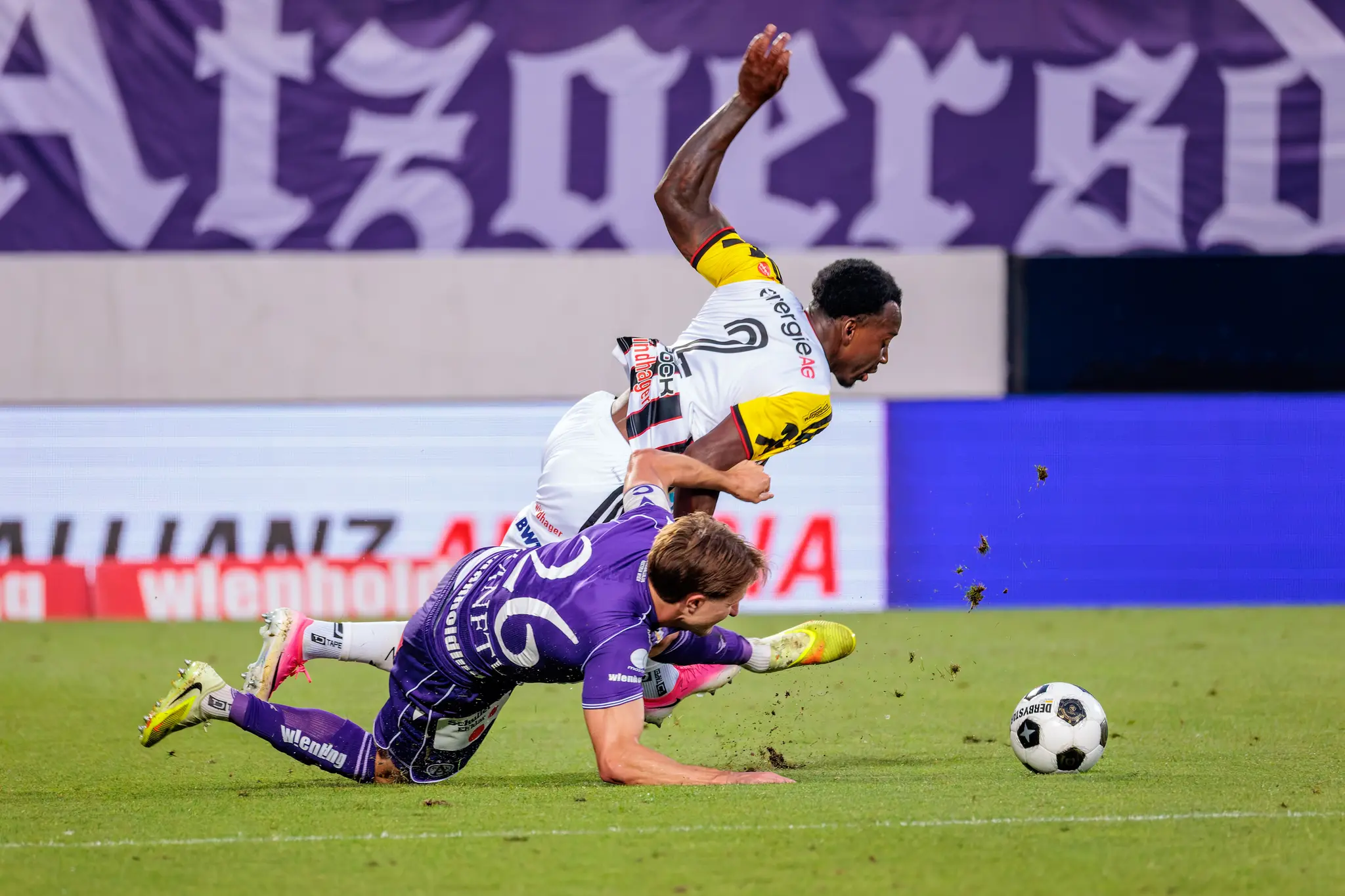 Harter Zweikampf: Austria-Spieler rutscht auf dem Bauch, LASK-Flügelspieler Bello stürzt über ihn, der Ball rollt daneben
