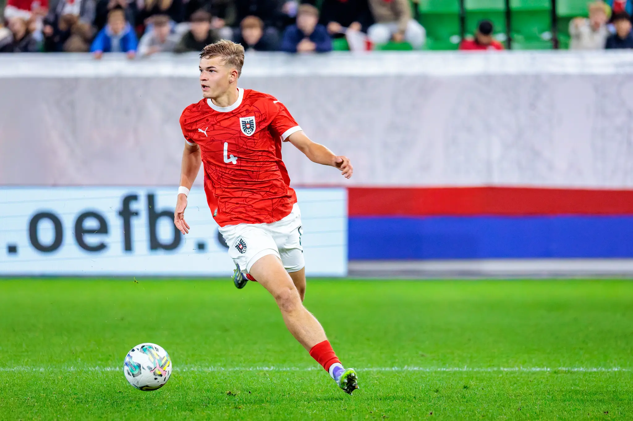 Der österreichische U21-Nationalspieler David Piczka dribbelt im roten Trikot mit der Nummer 4 dynamisch mit dem Ball am Fuß