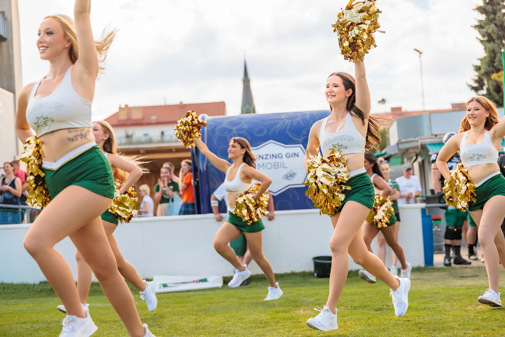 Dragons-Cheerleaderinnen im dynamischen Einlauf mit goldenen Pom-Poms, weiße Tops und grüne Röcke beim AFL-Playoff 2026