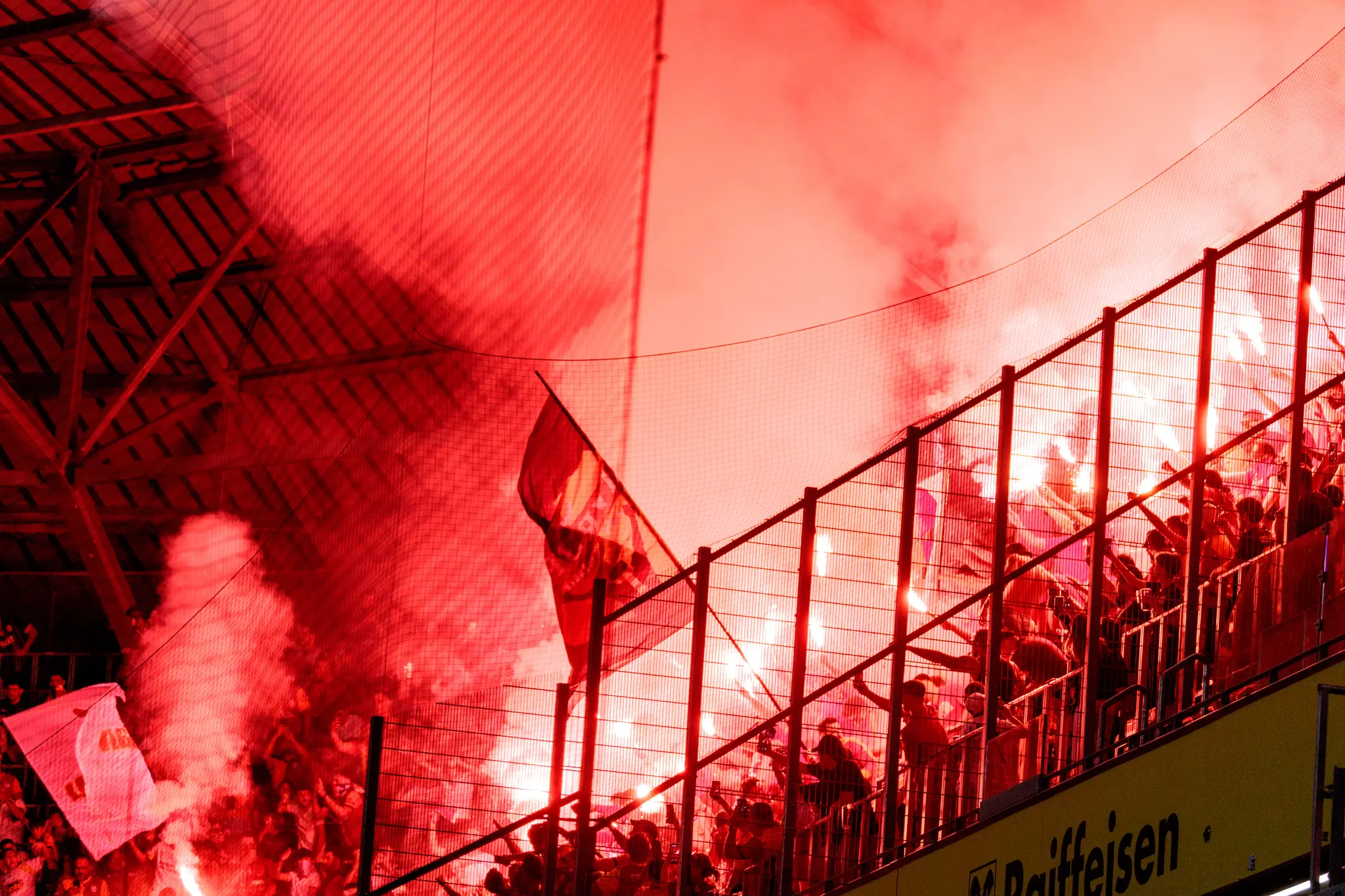 Galatasaray-Fans in der Raiffeisen Arena mit roten Fackeln und Fahnen, Rauch färbt die Tribüne in ein intensives Rot.