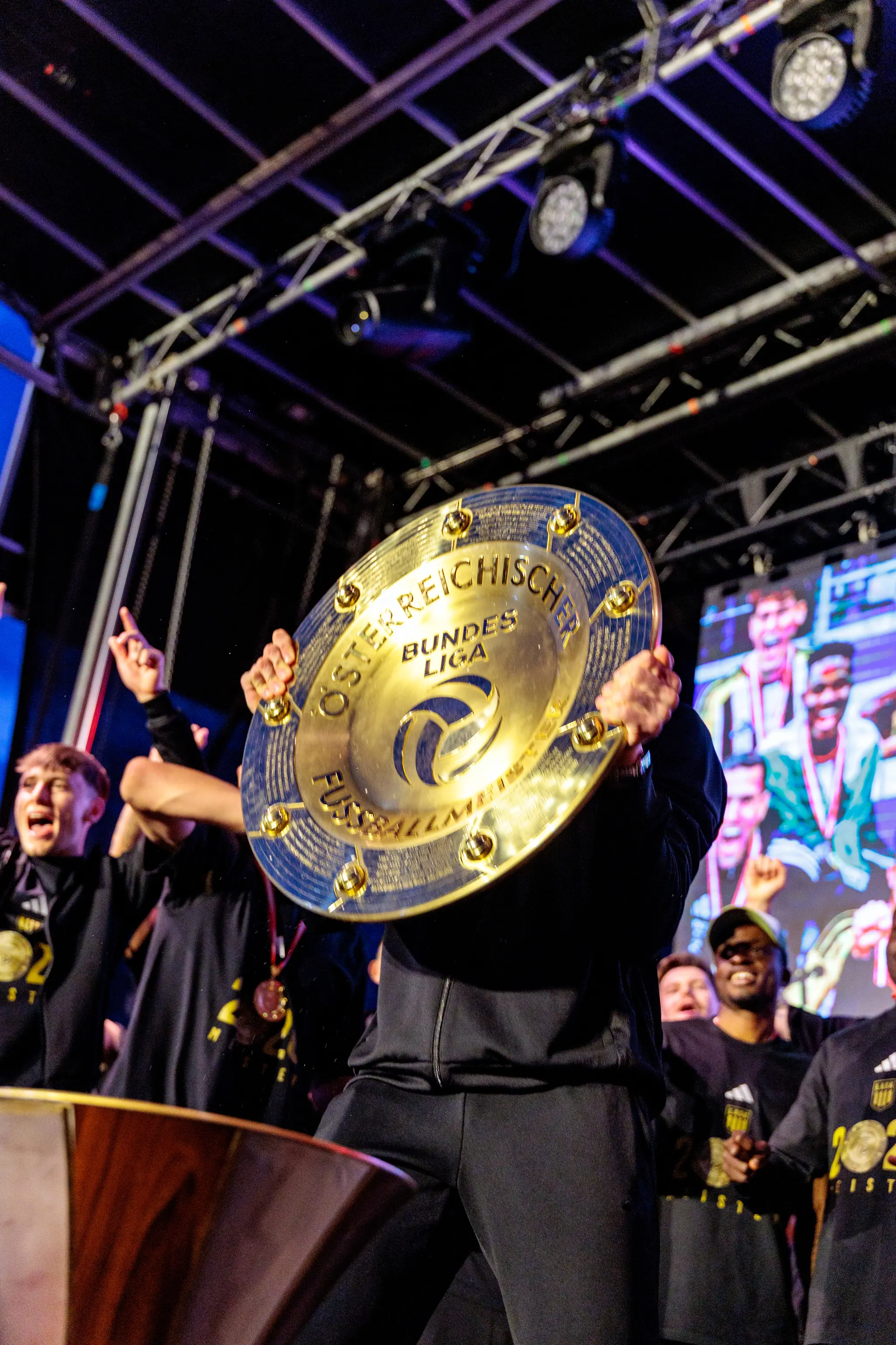 Ein Spieler hält den goldenen Meisterteller der österreichischen Bundesliga während der LASK-Meisterfeier direkt vor sein Gesicht