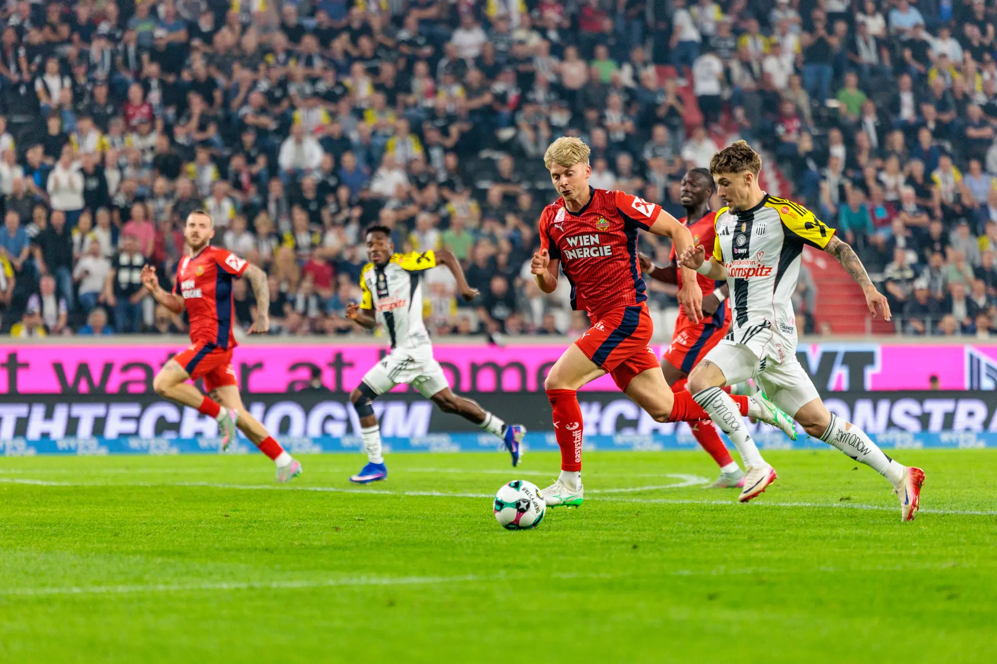 Ein Spieler des LASK und ein Spieler des SK Rapid befinden sich in einem intensiven Laufduell während der Bundesliga-Partie