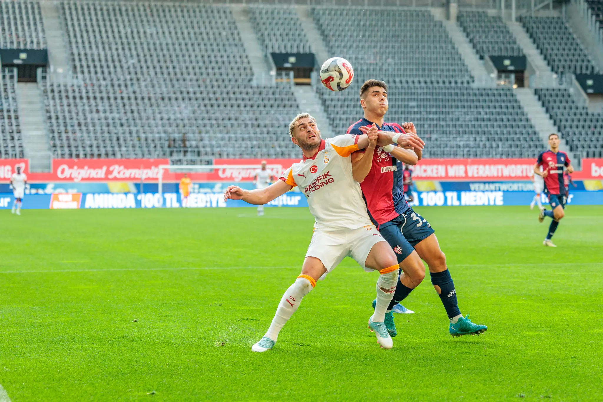 Zwei Fußballspieler köpfen den Ball in einem Kopfballduell während eines Vorbereitungsspiels vor leeren Rängen 