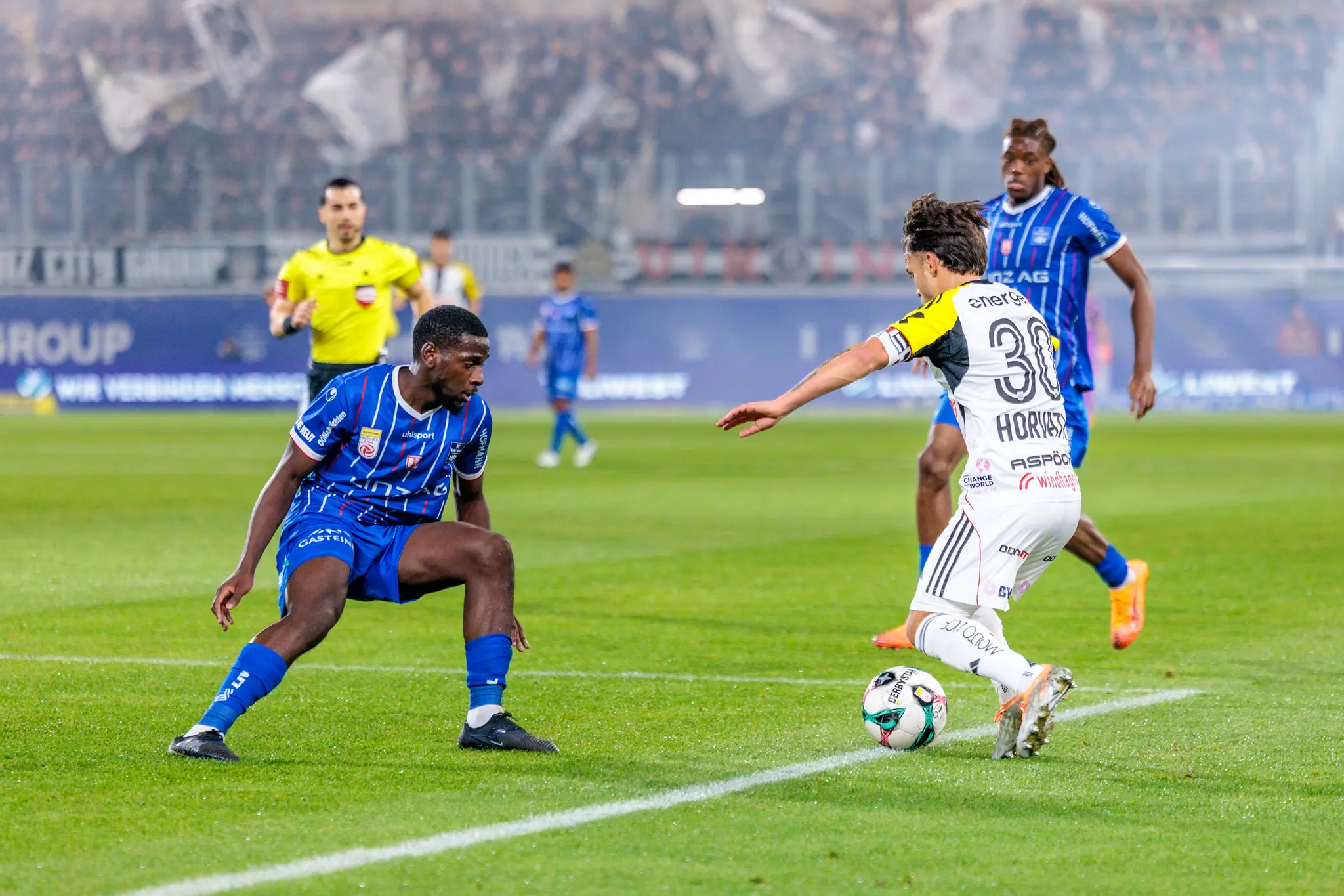 LASK-Kapitän Sascha Horvath dribbelt im intensiven Zweikampf gegen einen Verteidiger von Blau-Weiß Linz während des Linzer Derbys in der Fußball-Bundesliga
