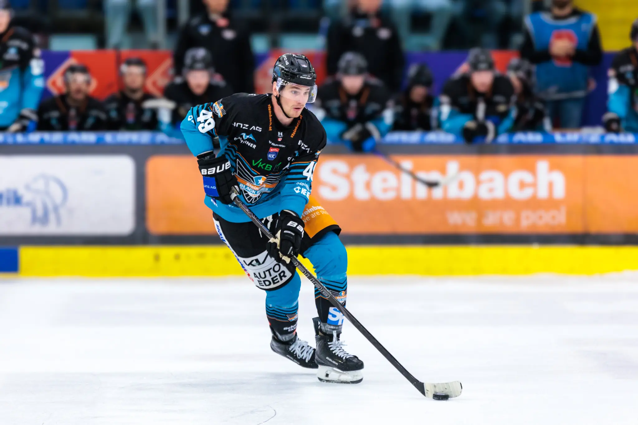 Der Eishockeyspieler Graham Knott von den Steinbach Black Wings Linz führt den Puck während eines Spiels konzentriert über das Eis