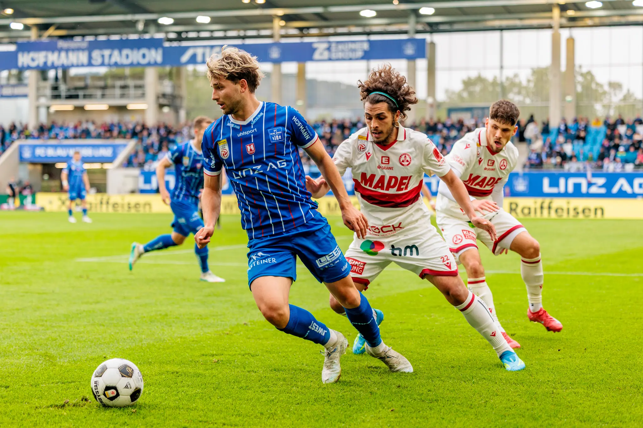 Ein intensiver Zweikampf zwischen Spielern von Blau-Weiß Linz und dem Grazer AK während eines Bundesliga-Spiels
