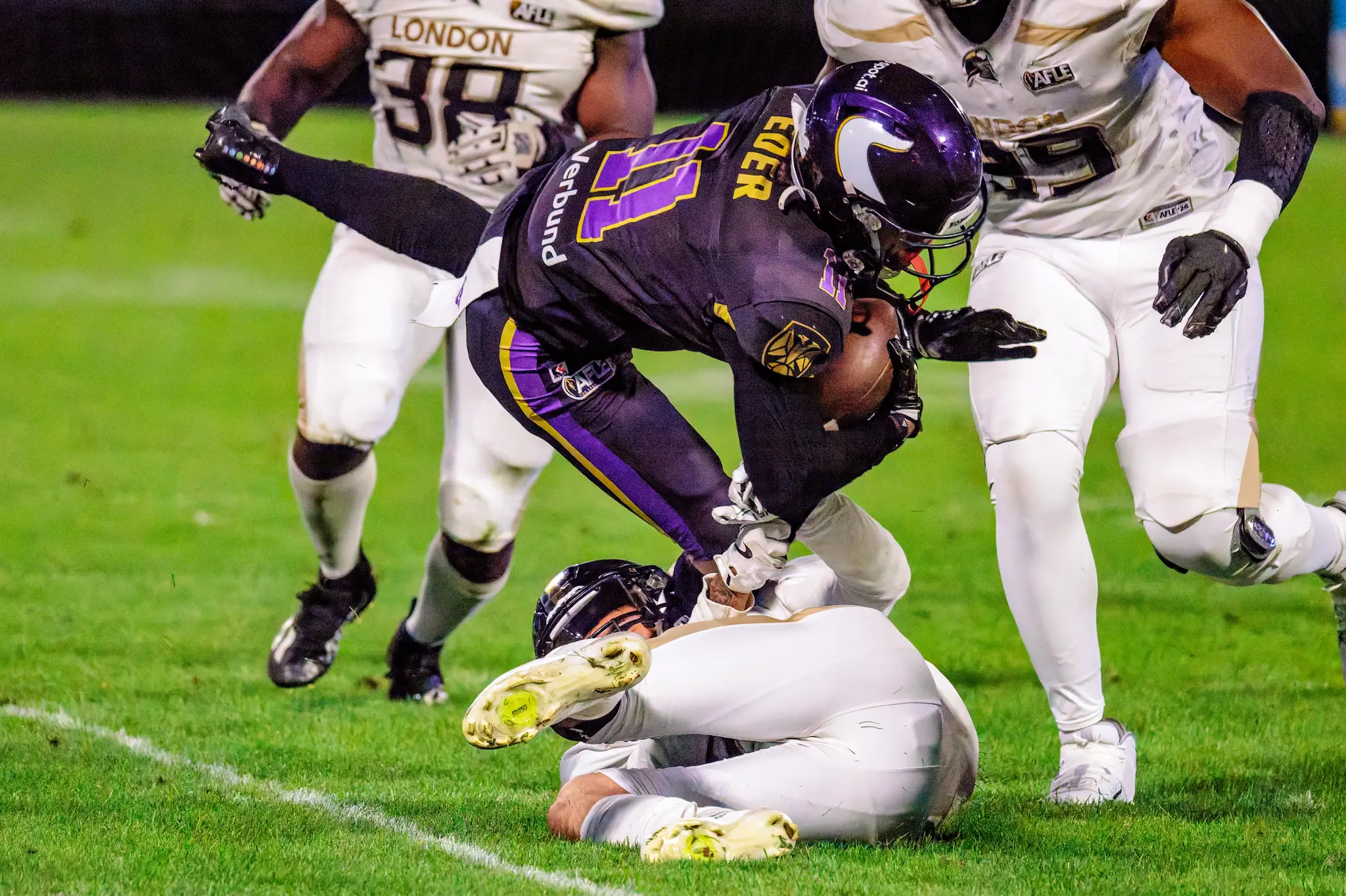 Fabian Eder (11) der Vienna Vikings fällt nach vorn über einen London-Verteidiger und drückt den Ball mit beiden Händen an die Brust – Passfang in den Schlussminuten des vierten Viertels.