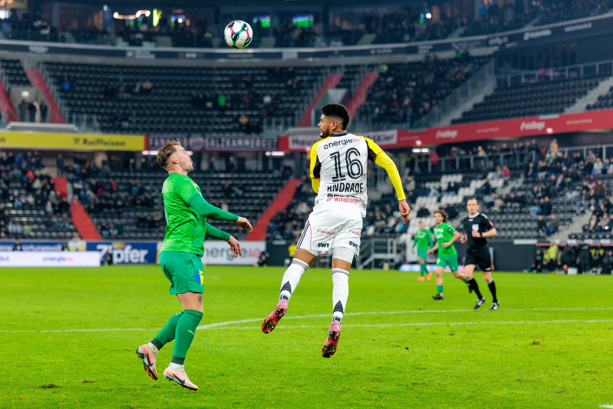 Ein Spieler des LASK mit der Trikotnummer 16 springt während eines Kopfballduells gegen einen Spieler der WSG Tirol zum Ball