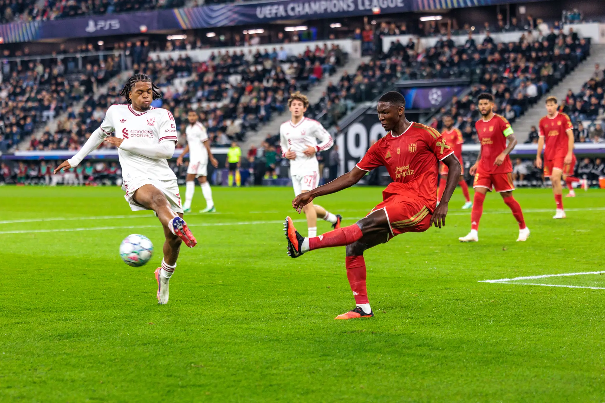 Ein LASK-Spieler klärt den Ball im eigenen Strafraum, nach dem Schuss bleibt sein Bein weit ausgestreckt, Rio Ngumoha (73) versucht vergeblich dazwischenzukommen.