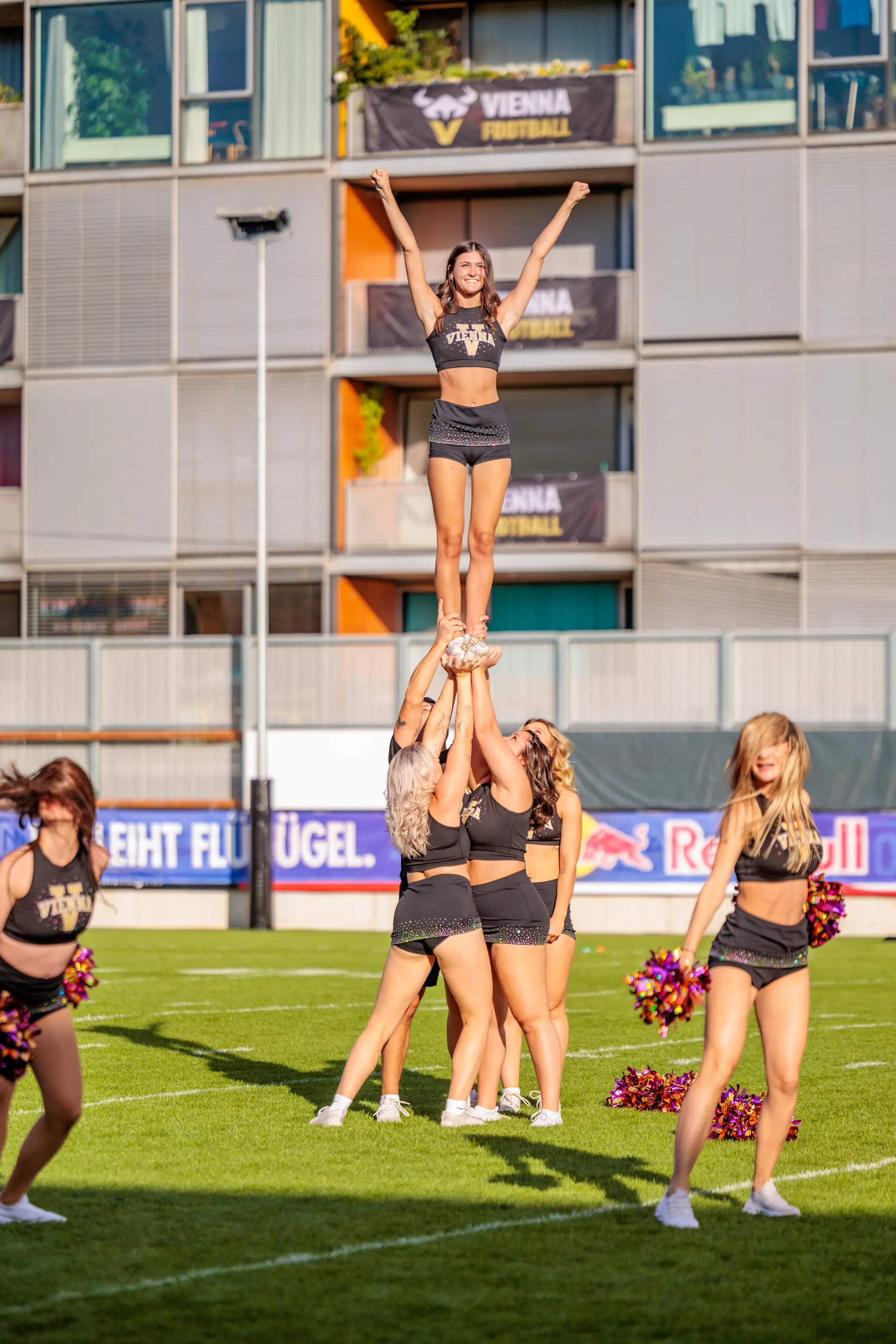 Cheer-Stunt vor dem Anpfiff: Eine Flyerin des Vienna Vikings Cheer Squads balanciert über den Händen ihrer Bases, die Arme zum V gereckt – Stimmung vor dem AFLE-Halbfinale in Wien.