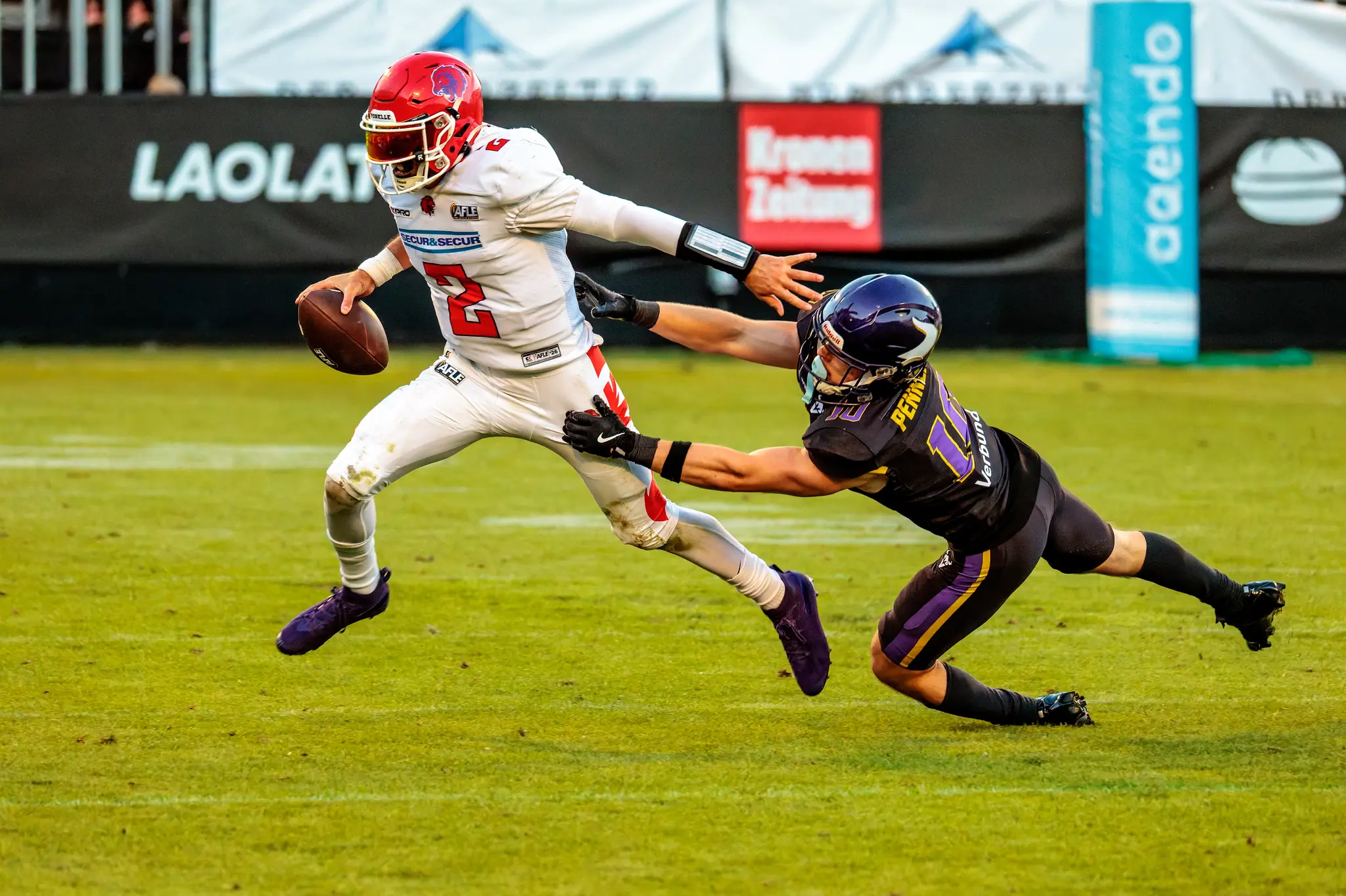 Hautnah: Ein Vikings-Verteidiger (10) wirft sich gestreckt über den Rasen nach dem Red-Lions-Quarterback (Nr. 2), doch der Ballträger entwischt im letzten Moment – kämpferisch bis zur Schlusssirene.