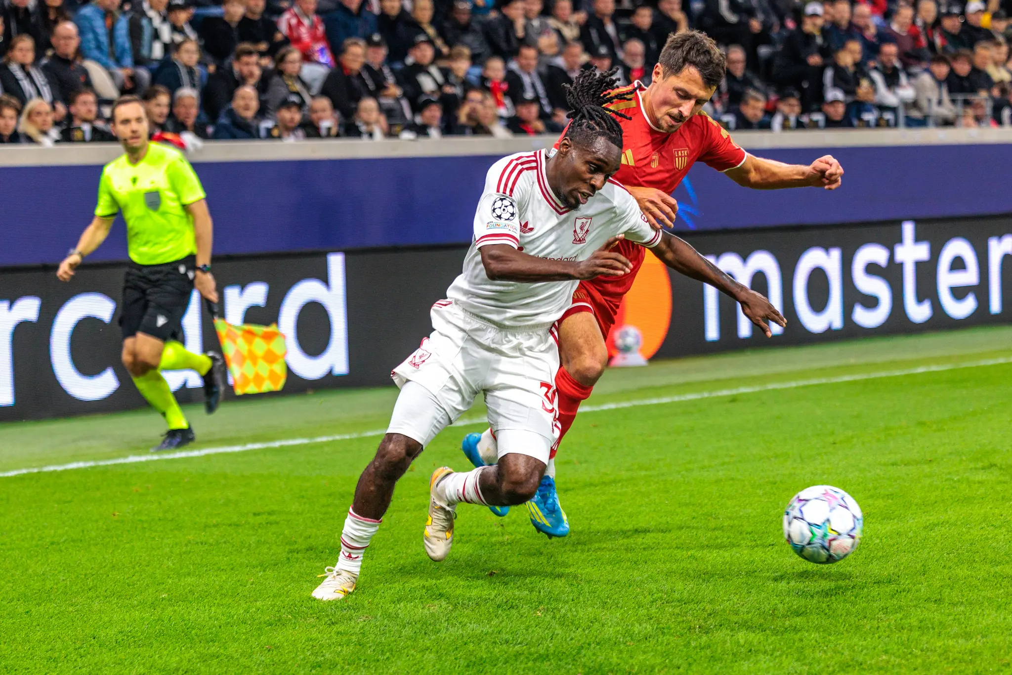 Rio Ngumoha (73) kämpft mit einem LASK-Spieler eng am Ball, im Hintergrund läuft der Linienrichter mit erhobener Fahne mit.
