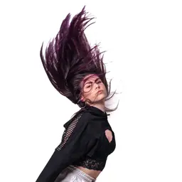 Eine junge Frau mit lila Haaren, die dynamisch aufgewirbelt sind, trägt ein schwarzes Crop-Top mit Netzeinsätzen und blickt selbstbewusst in die Kameralens: EF-S18-135mm f/3.5-5.6 IS STM