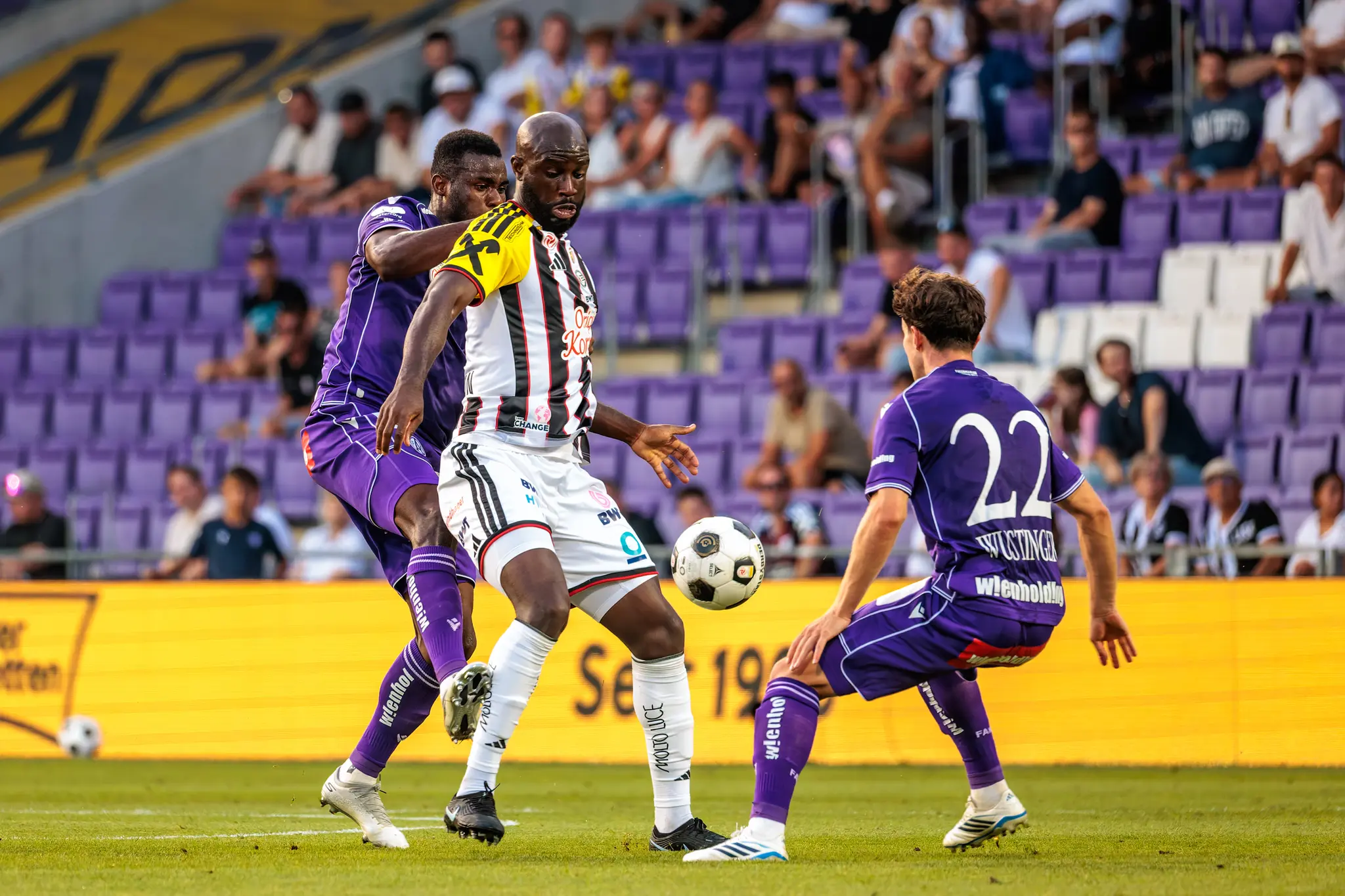 LASK-Stürmer Adeniran wird von zwei Austria-Spielern bedrängt und behauptet im Zweikampf den Ball