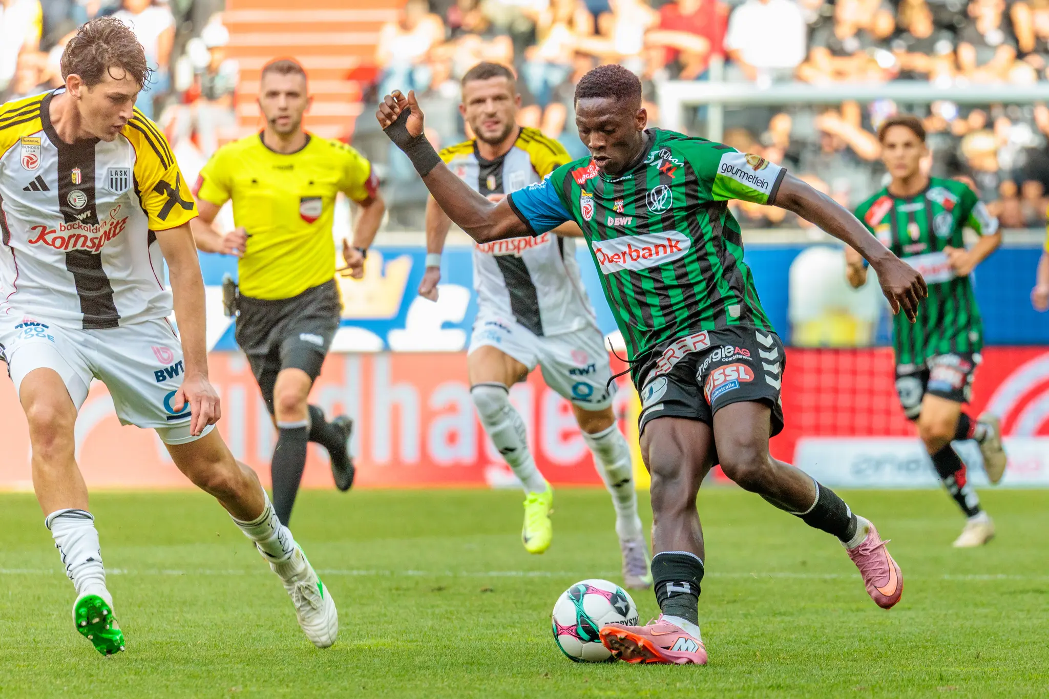 Ein Spieler von SV Ried dribbelt den Ball nach vorne, während ein Spieler des LASK verteidigt, während eines Bundesliga-Fußballspiels