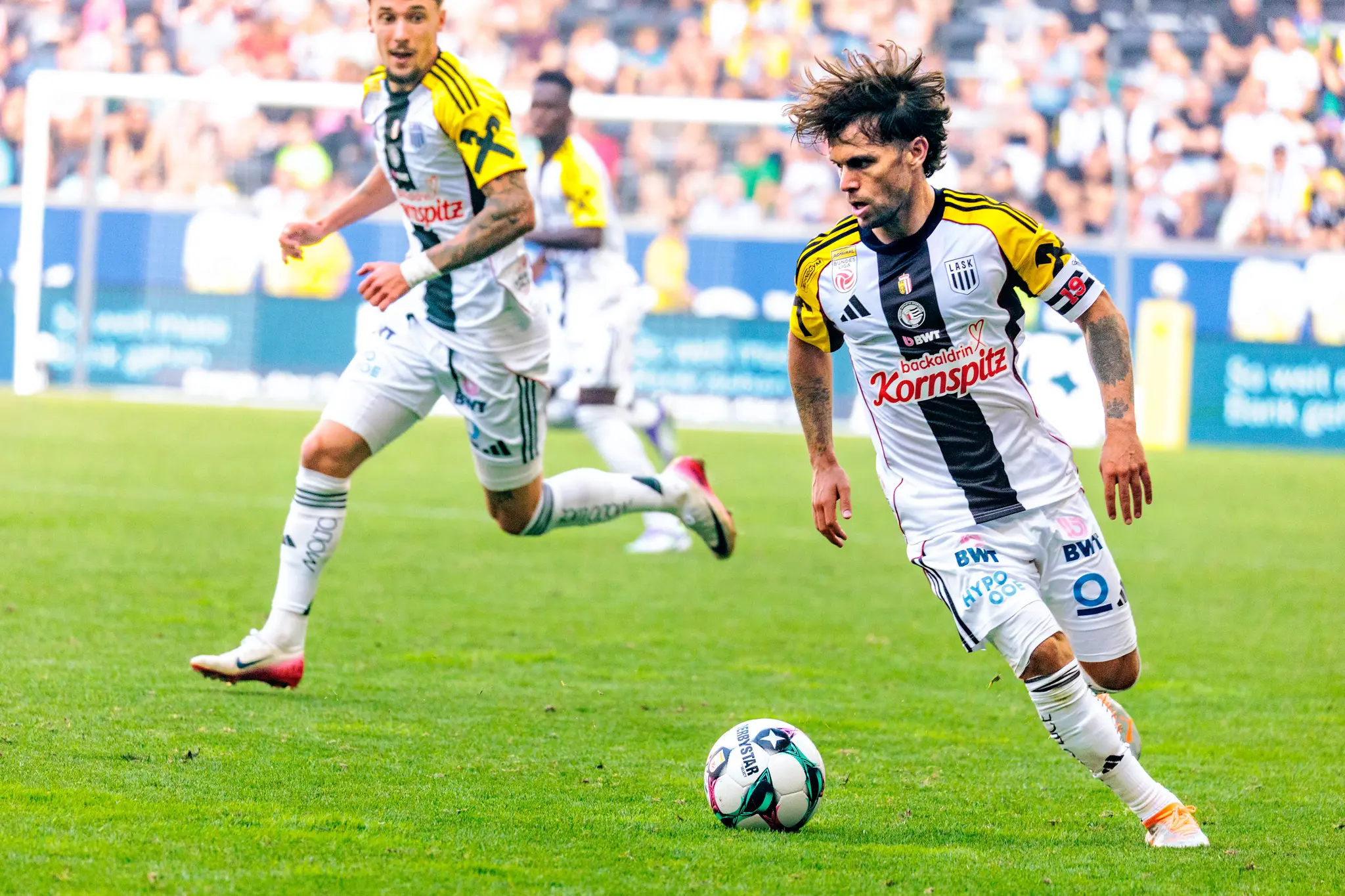 Der LASK-Kapitän Sascha Horvath treibt mit wilder Frisur und konzentriertem Blick den Ball nach vorne