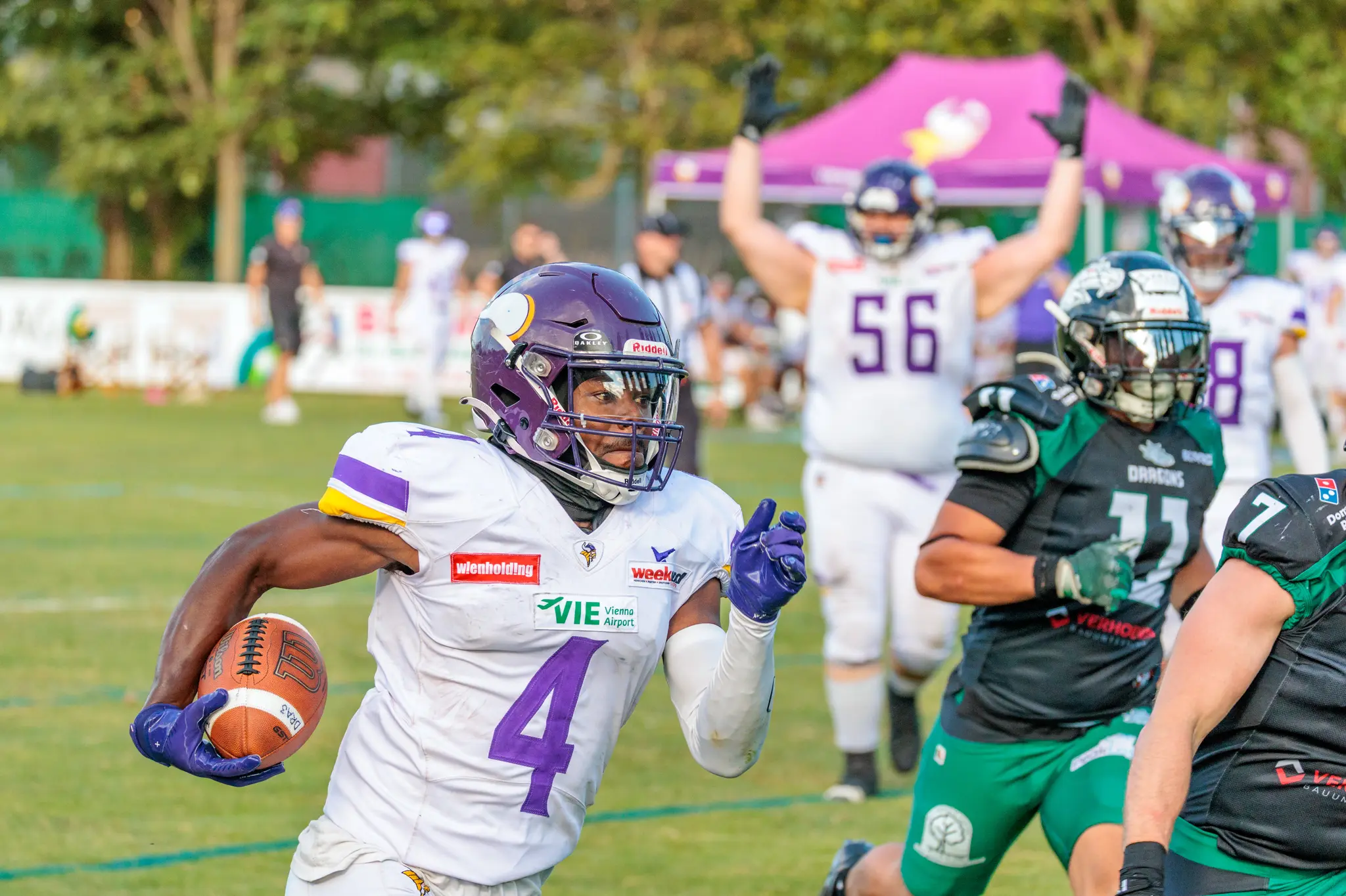 Vienna Vikings Läufer im weißen Trikot mit Purple wird von mehreren Danube Dragons-Spielern in grünen Trikots gestoppt – harter Tackle im AFL-Playoff 2026