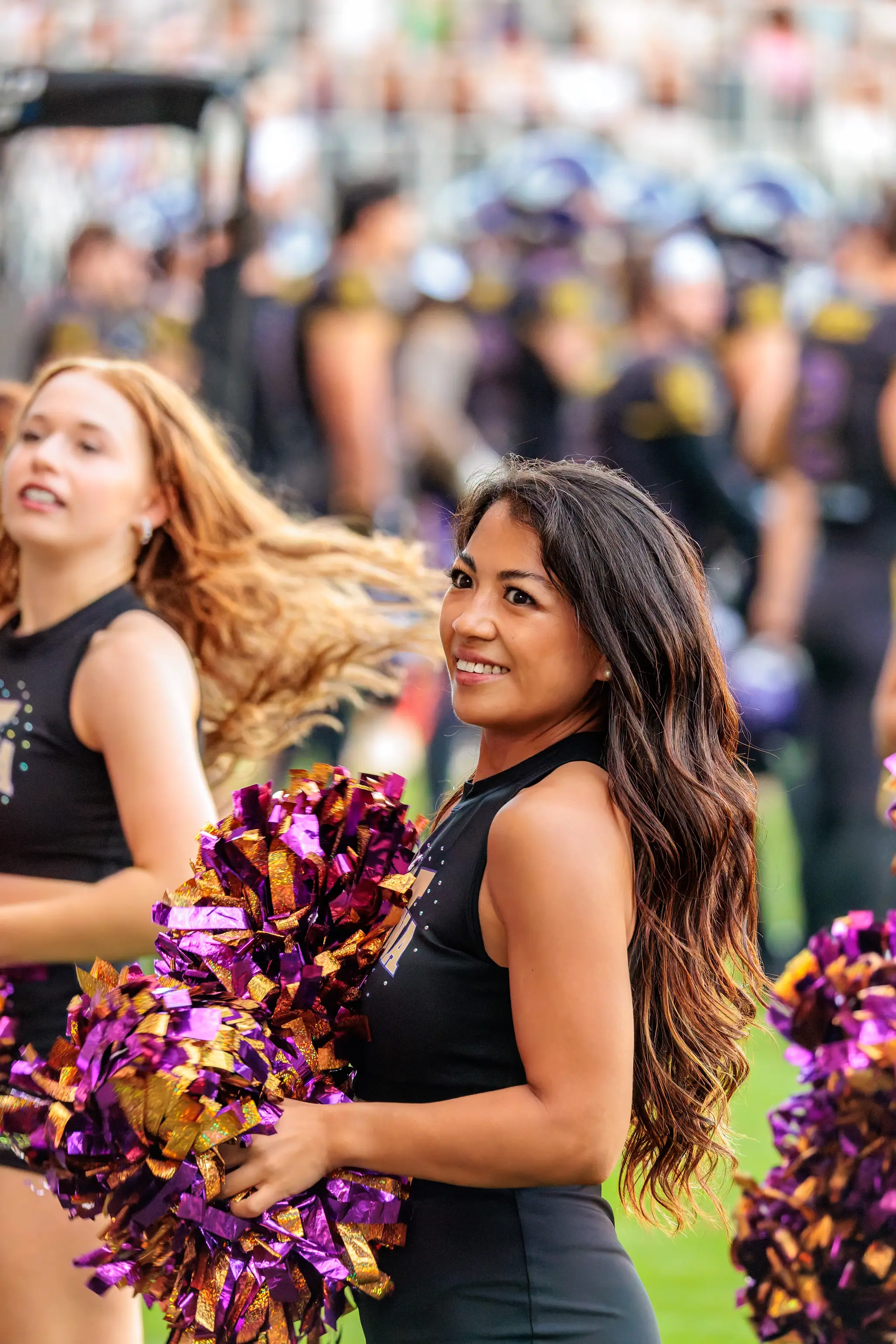 In der Bildmitte lächelt eine Tänzerin des Vienna Vikings Cheer Squads in die Kamera, die lila-goldenen Pompons vor dem Körper.