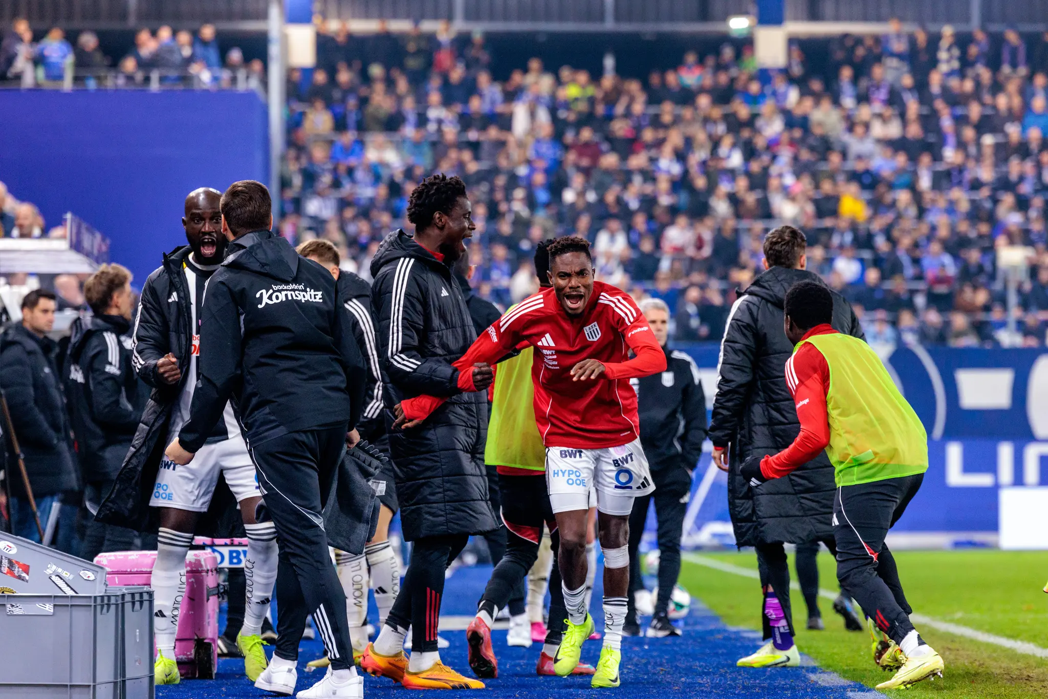 LASK-Stürmer Moses Adeniran feiert sein Tor im Linzer Derby emotional mit den jubelnden Spielern und Betreuern auf der Ersatzbank
