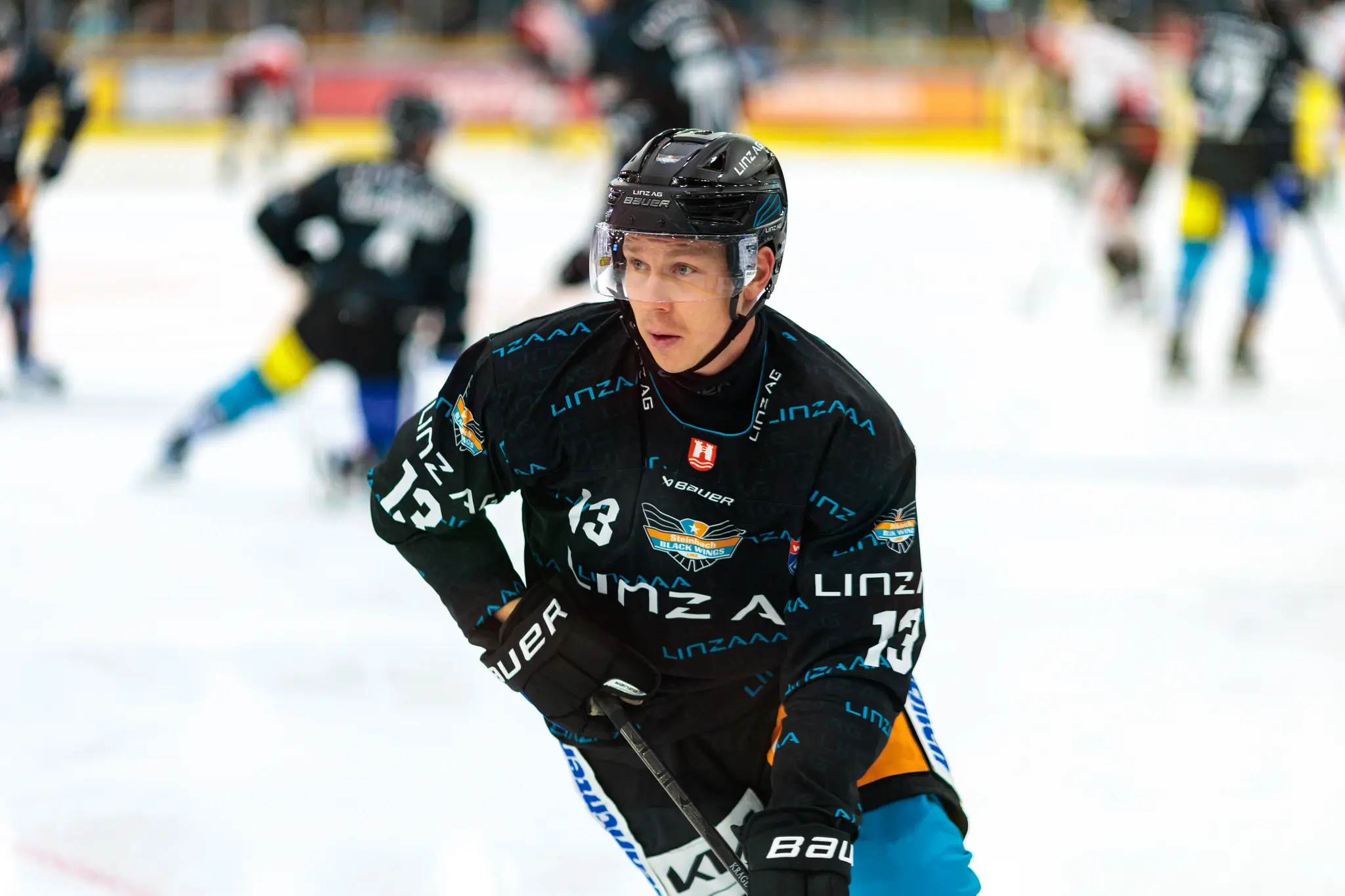 Eishockeyspieler Gerd Kragl mit der Nummer 13 der Steinbach Black Wings Linz steht in seinem schwarzen Trikot und Helm auf dem Eis