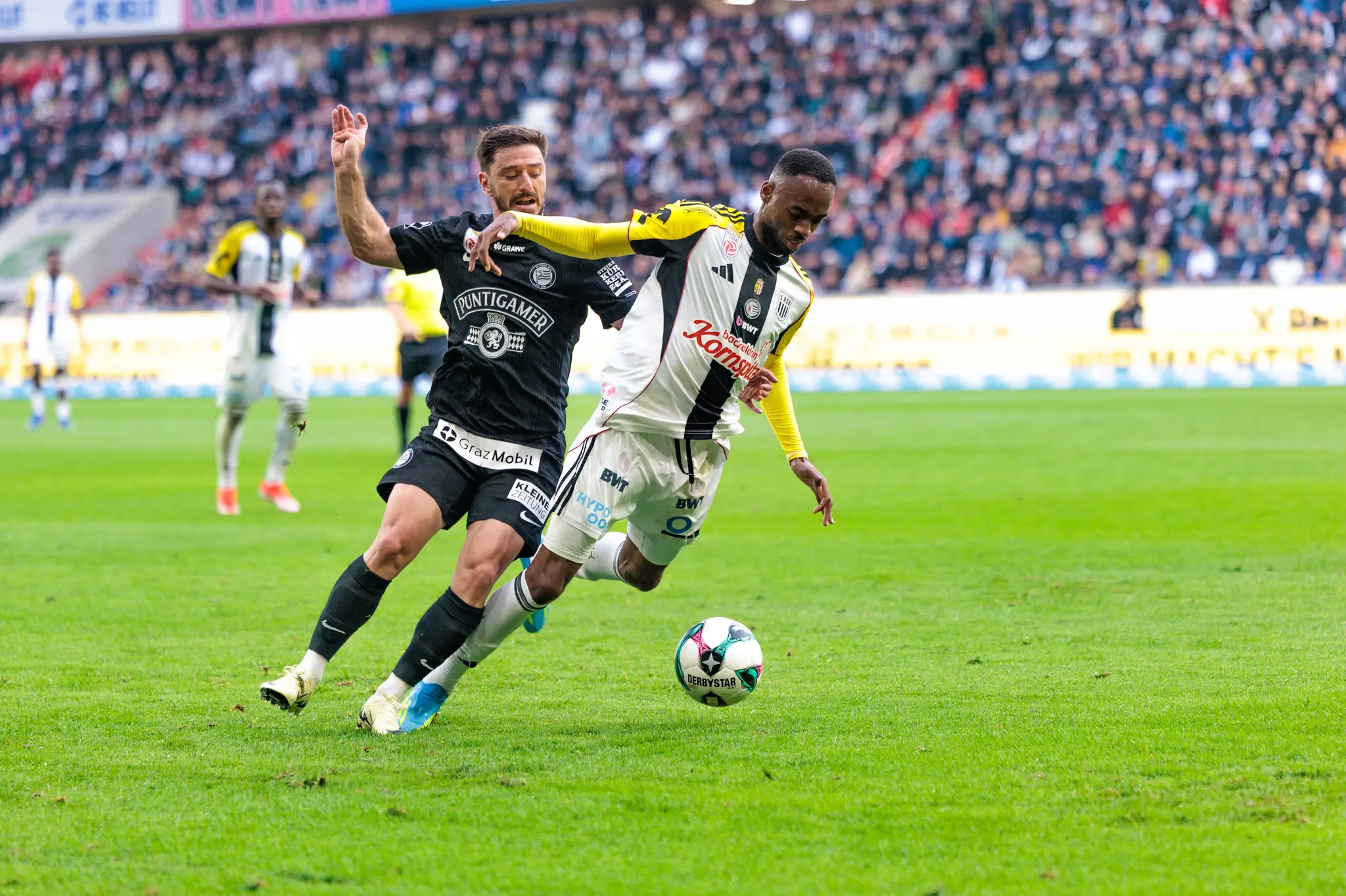 Ein LASK-Spieler führt den Ball im Zweikampf gegen einen Spieler von Sturm Graz