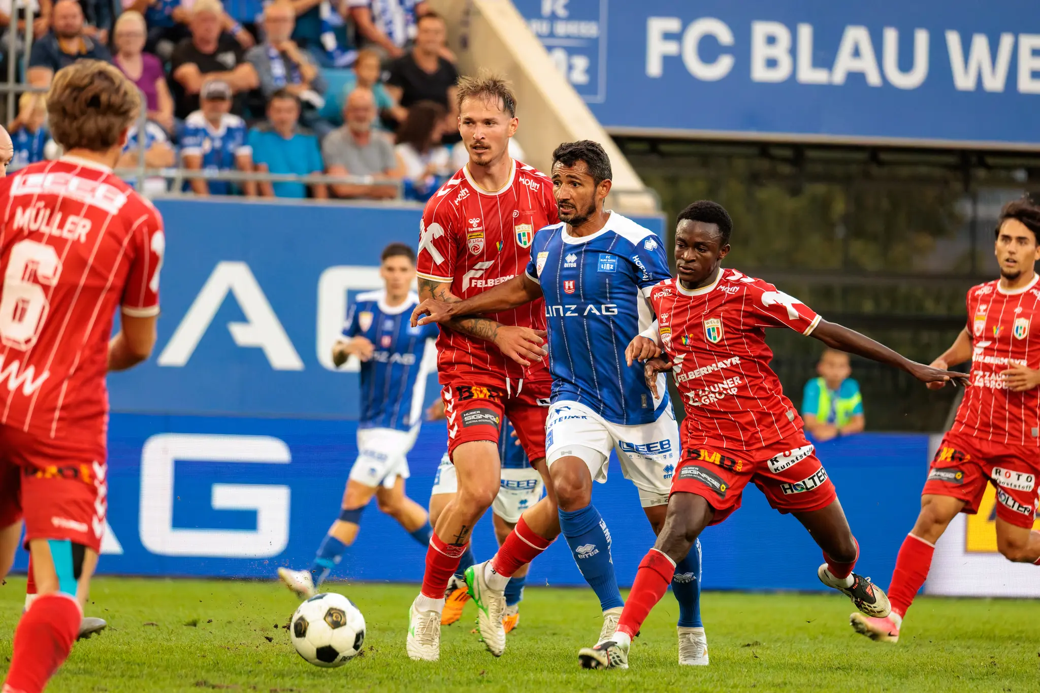 Ronivaldo vom FC Blau-Weiß Linz wird im Mittelfeld von mehreren Welser Spielern umringt; der Ball liegt vor ihm am Boden, links steht der eingewechselte Pascal Müller (6).