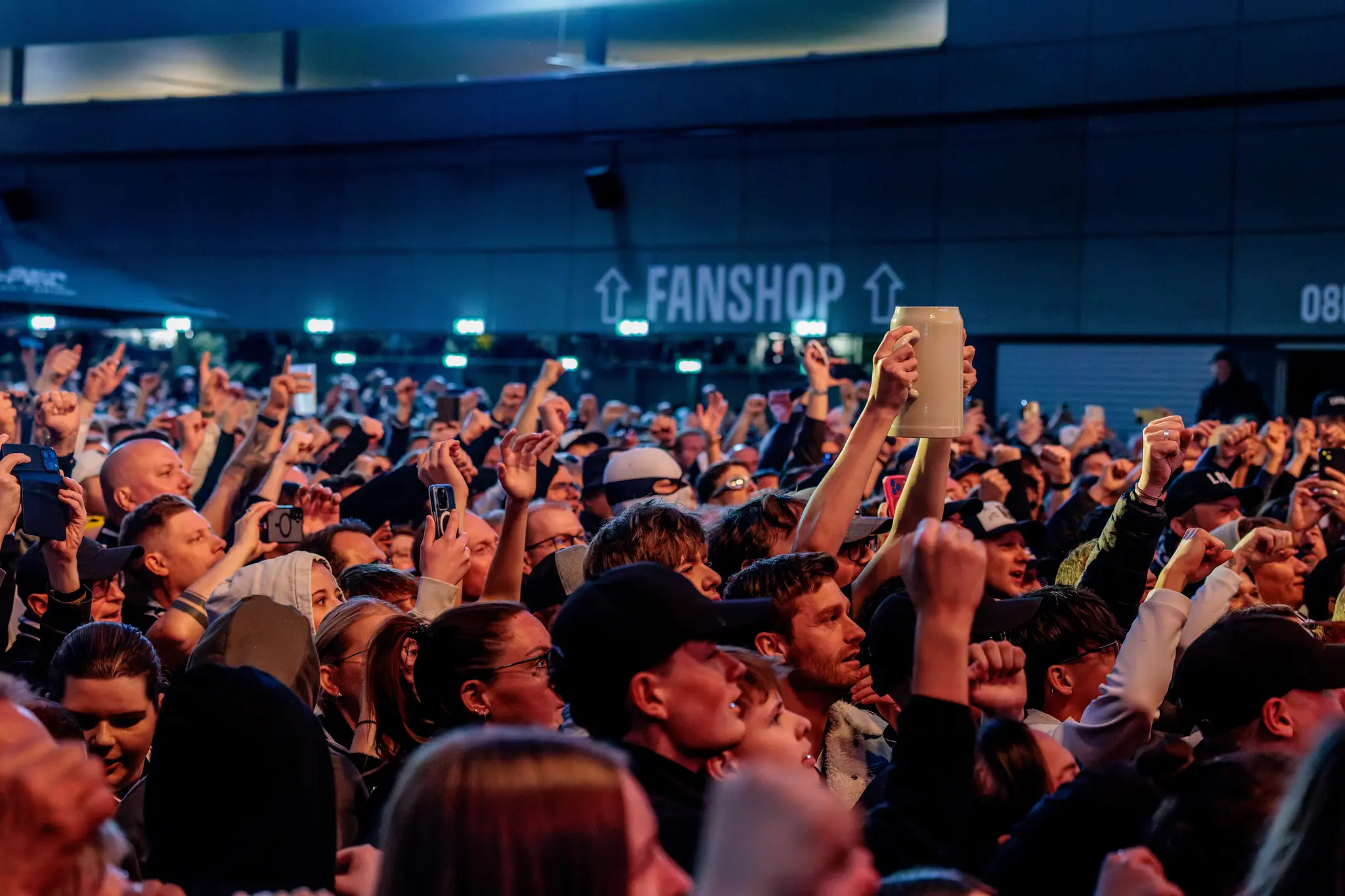 Begeisterte LASK-Fans feiern mit erhobenen Bierkrügen in der Fanzone während der historischen Meisterfeier in Linz
