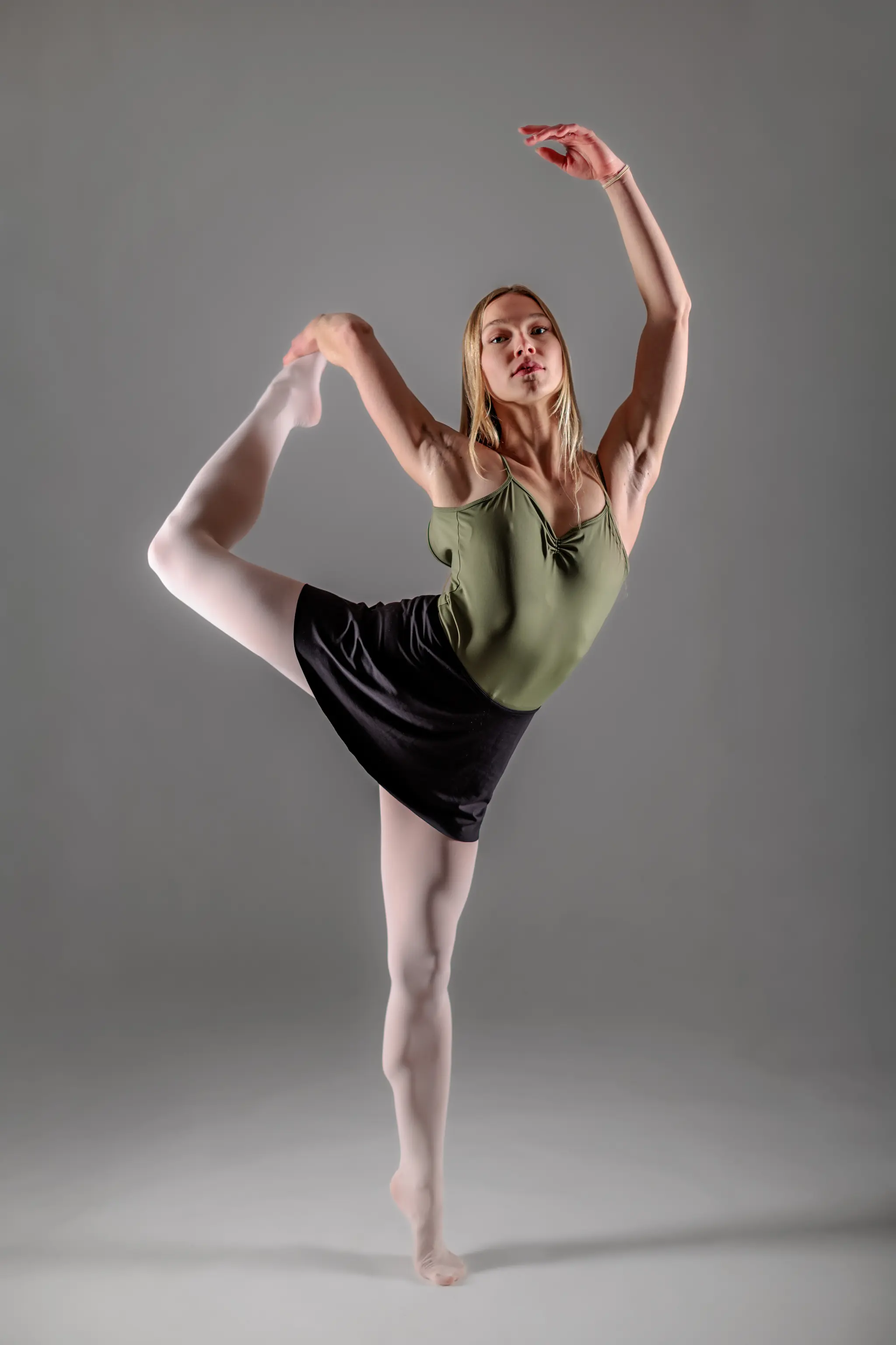 Model Kathrin demonstriert künstlerische Körperbeherrschung in einer eleganten, stehenden Ballett-Pose während einer professionellen Studio-Session