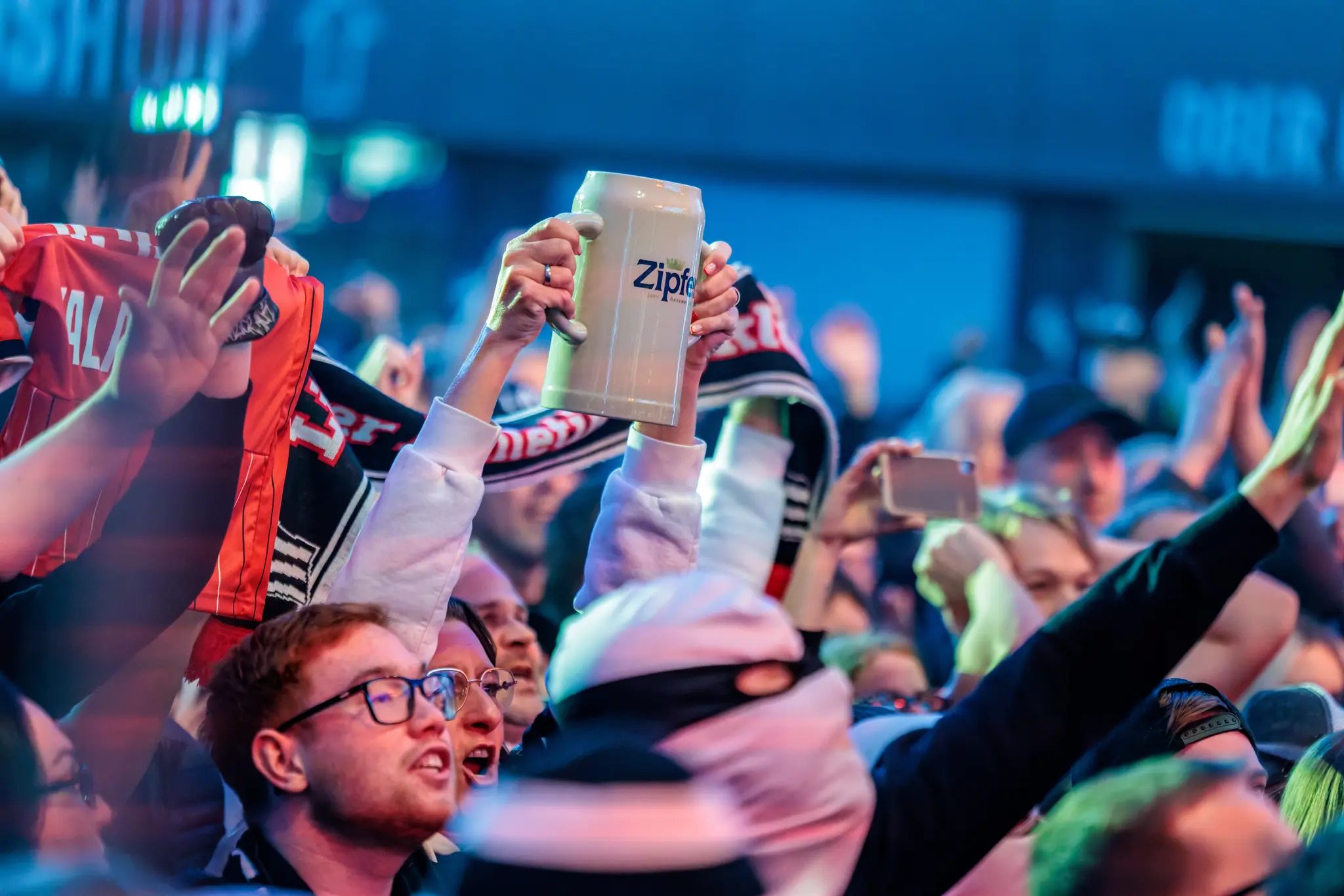 Begeisterte LASK-Fans heben beim Jubel während der Meisterfeier einen Bierkrug in die Höhe