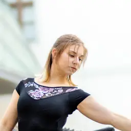 Porträt einer jungen Frau mit blondem Haar, die ein schwarzes Oberteil mit floralem Muster trägt und nachdenklich nach unten blickt lens: EF85mm f/1.8 USM