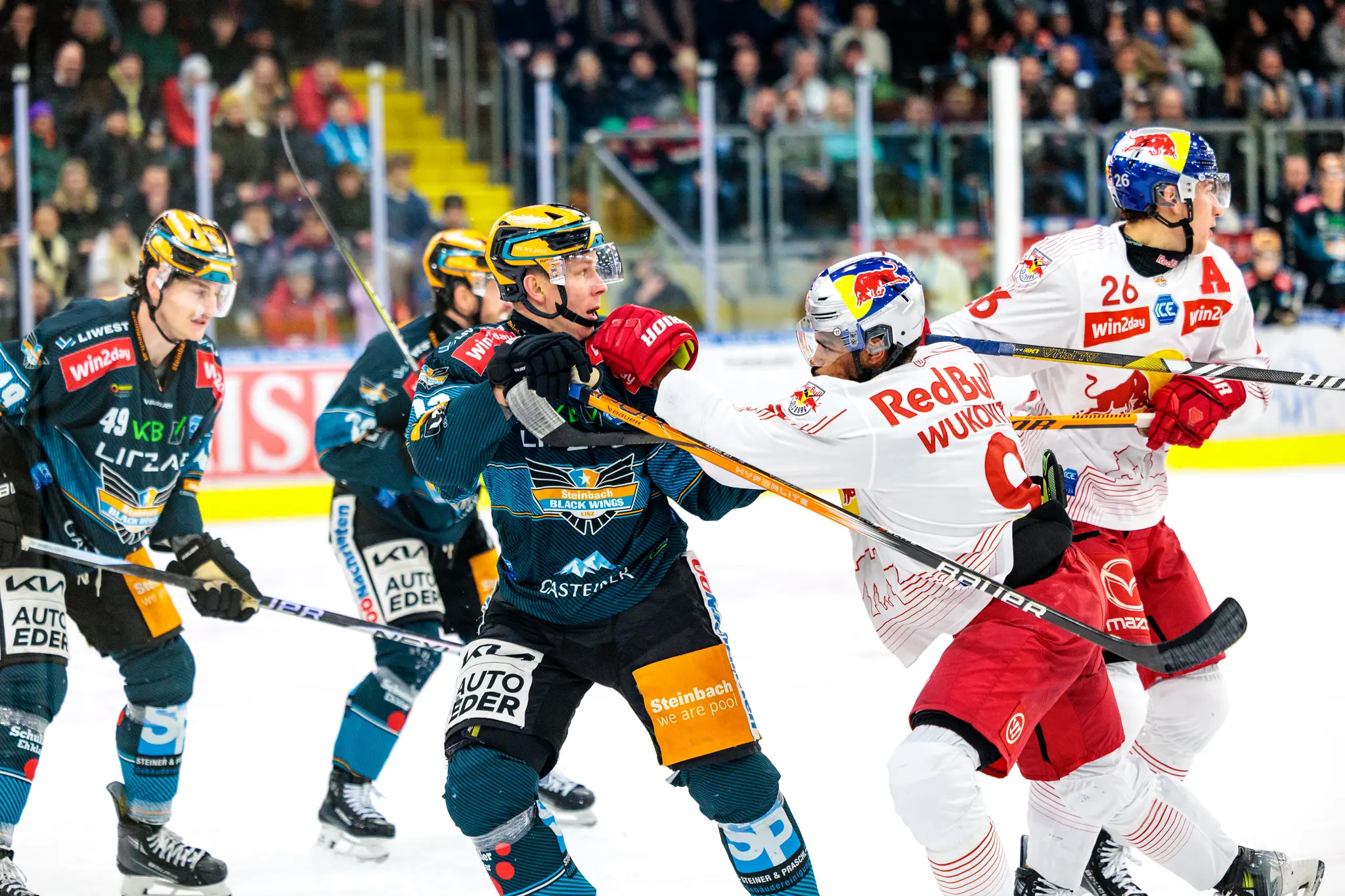 Zwei Eishockeyspieler in dunklen und weißen Trikots liefern sich einen Zweikampf auf dem Eis während eines packenden Spiels 
