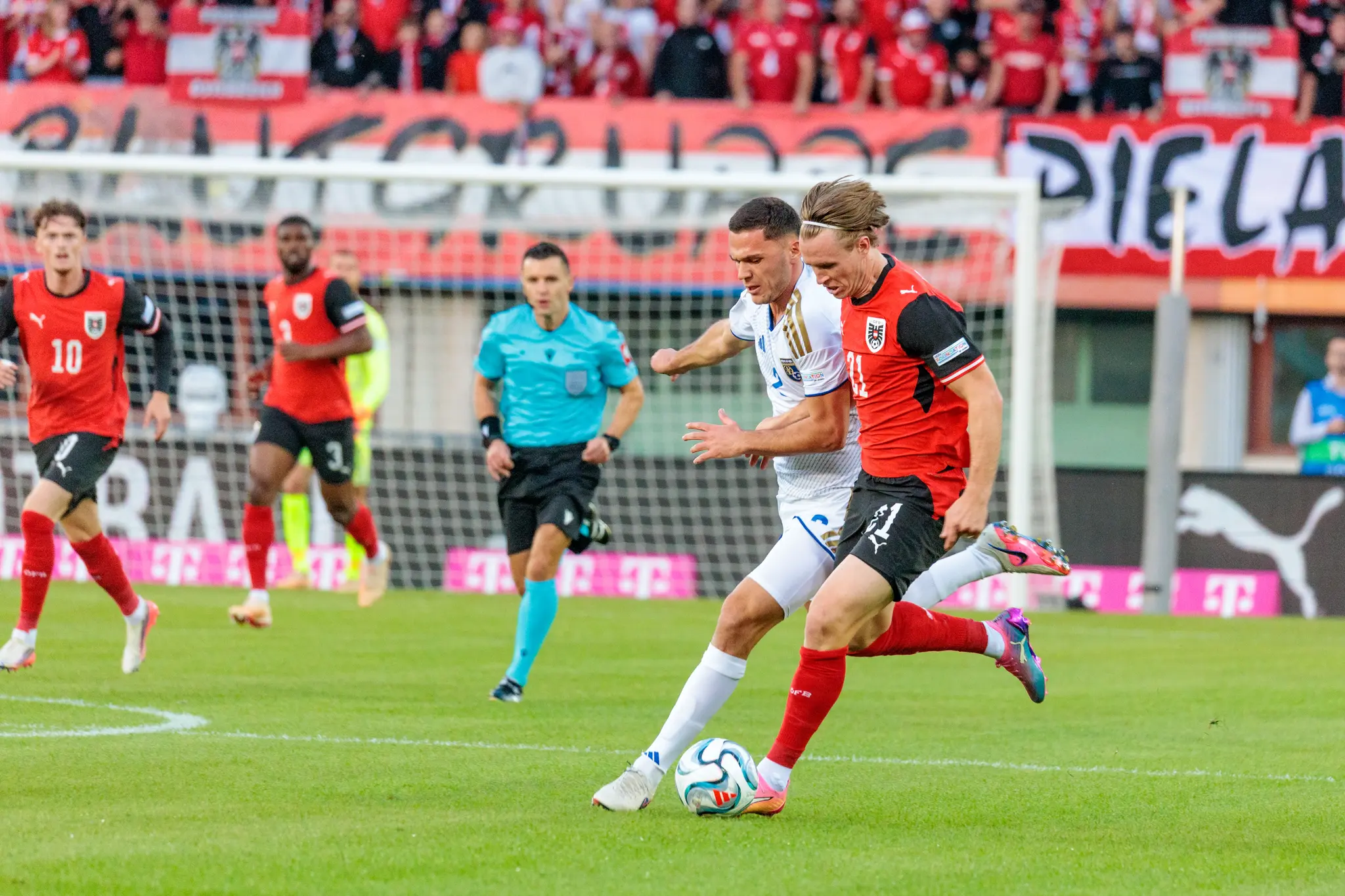 Patrick Wimmer (21) führt den Ball durch das Mittelfeld, während ein Gegenspieler des Kosovo ihm nachsetzt.