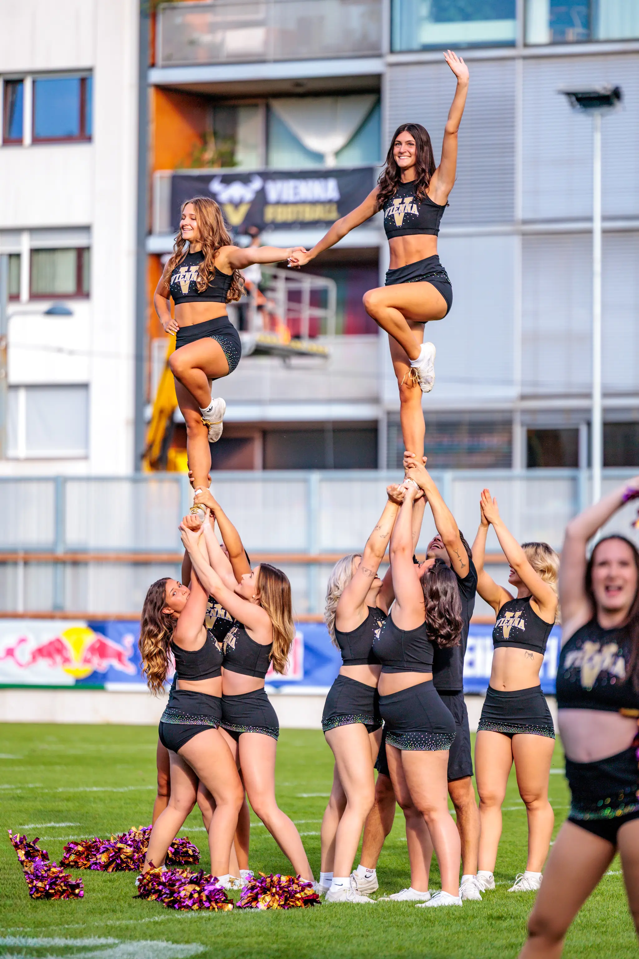 Doppelter Stunt des Vienna Vikings Cheer Squads: Zwei Flyerinnen balancieren auf einer Hand und reichen sich die Hände, während die Bases unten sichern – Showeinlage vor dem Spiel.