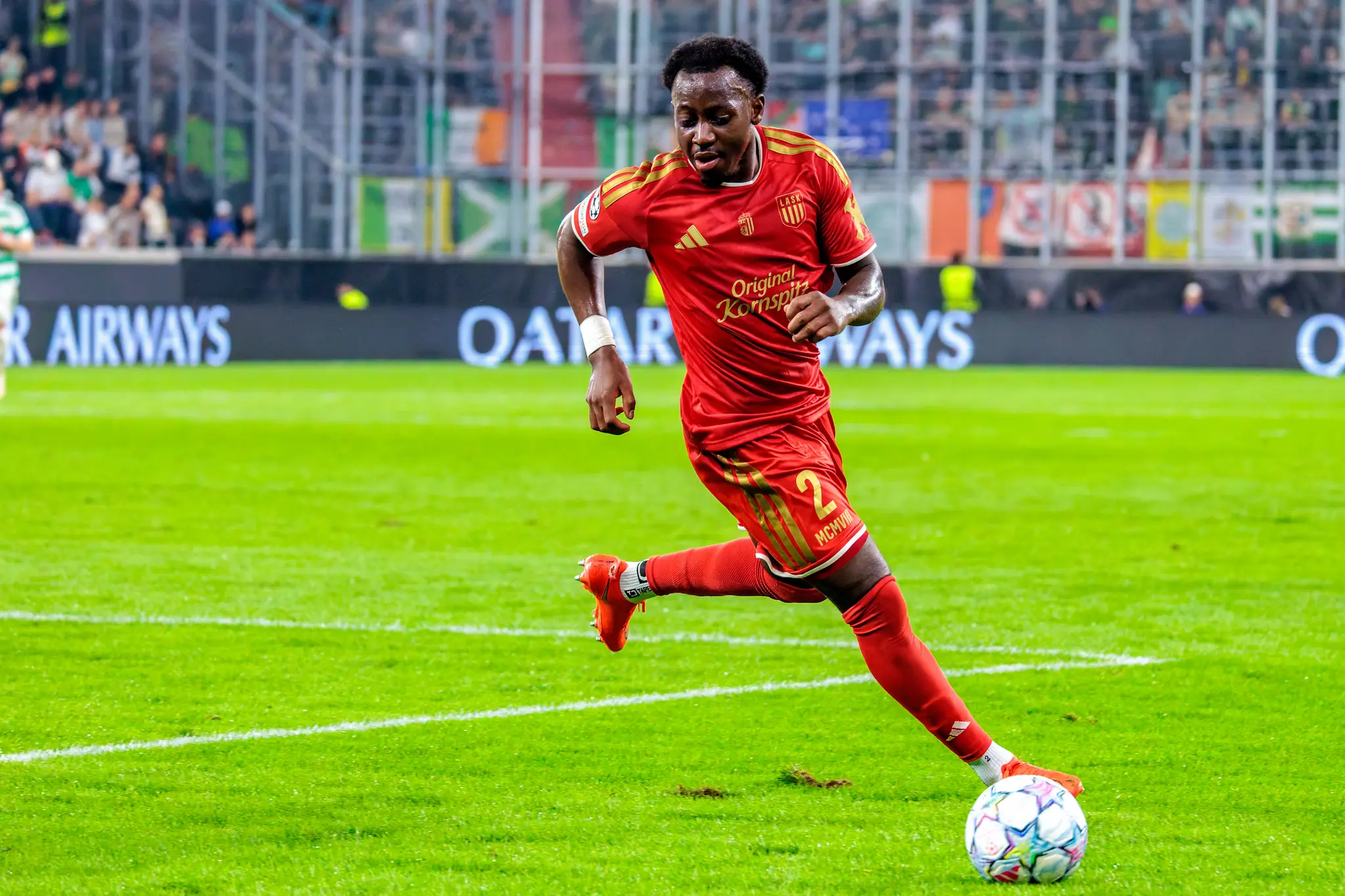 LASKs Bello führt den Ball im Sprint über den nassen Rasen.