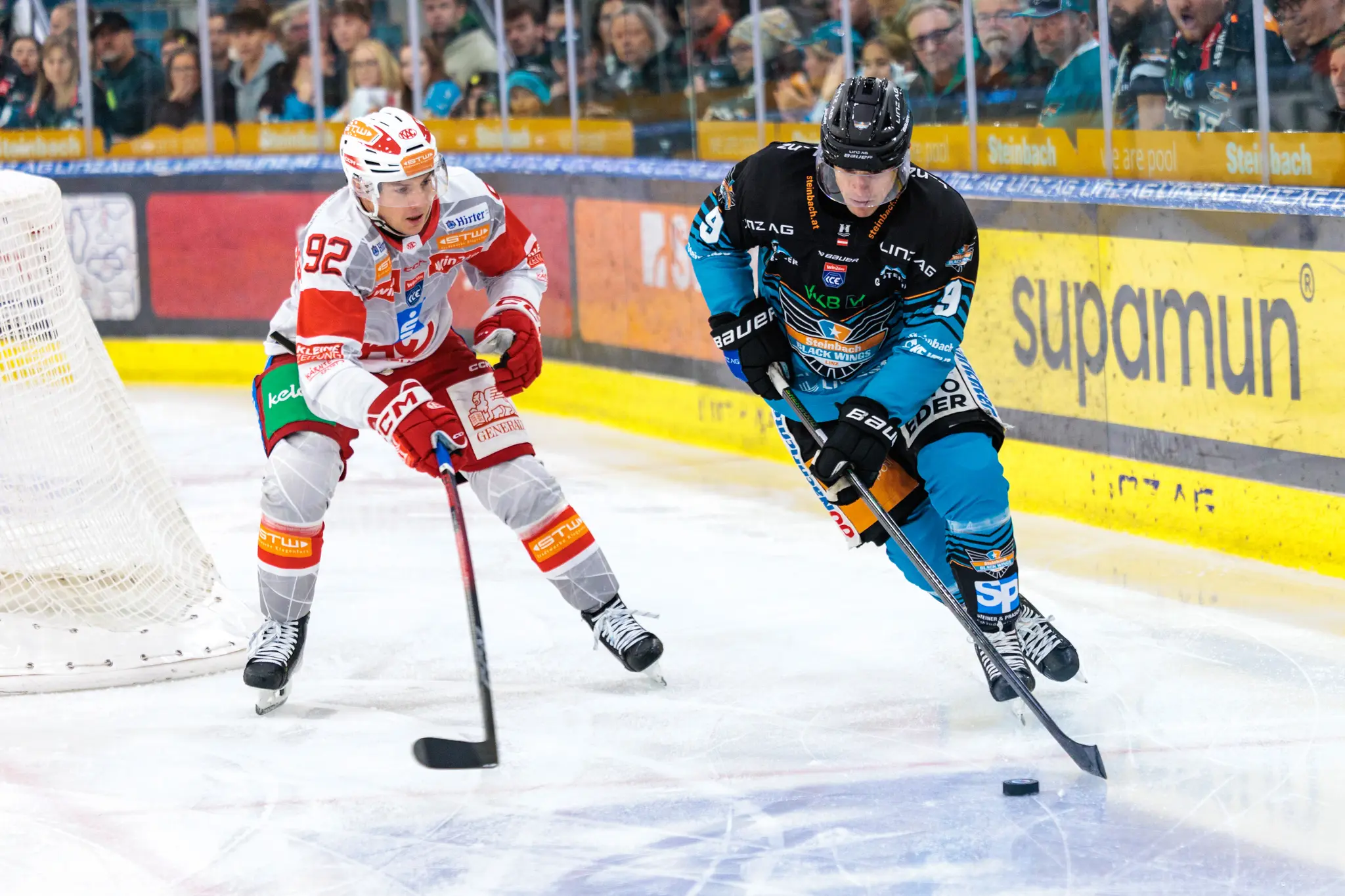 Der Eishockeyspieler Greg Moro von den Black Wings Linz führt den Puck und wird dabei von Clemens Unterweger vom EC-KAC vor dem Tor verteidigt