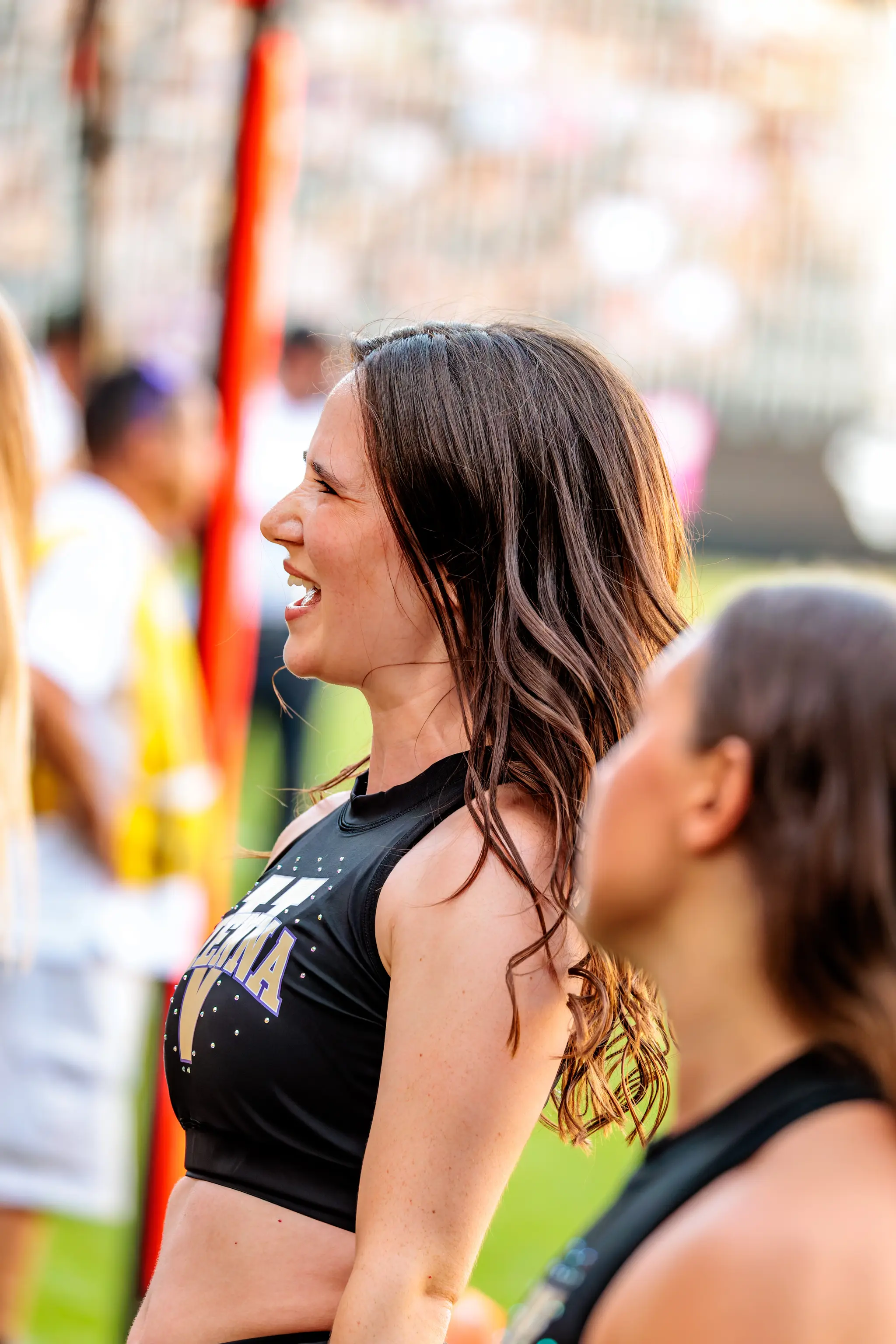 Cheerleaderin der Vienna Vikings in schwarzem, glitzerndem Tanzoutfit mit violett-goldenen Details.
