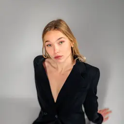 Porträt von Kathrin Mayr in einem eleganten schwarzen Blazer vor einem neutralen grauen Hintergrund