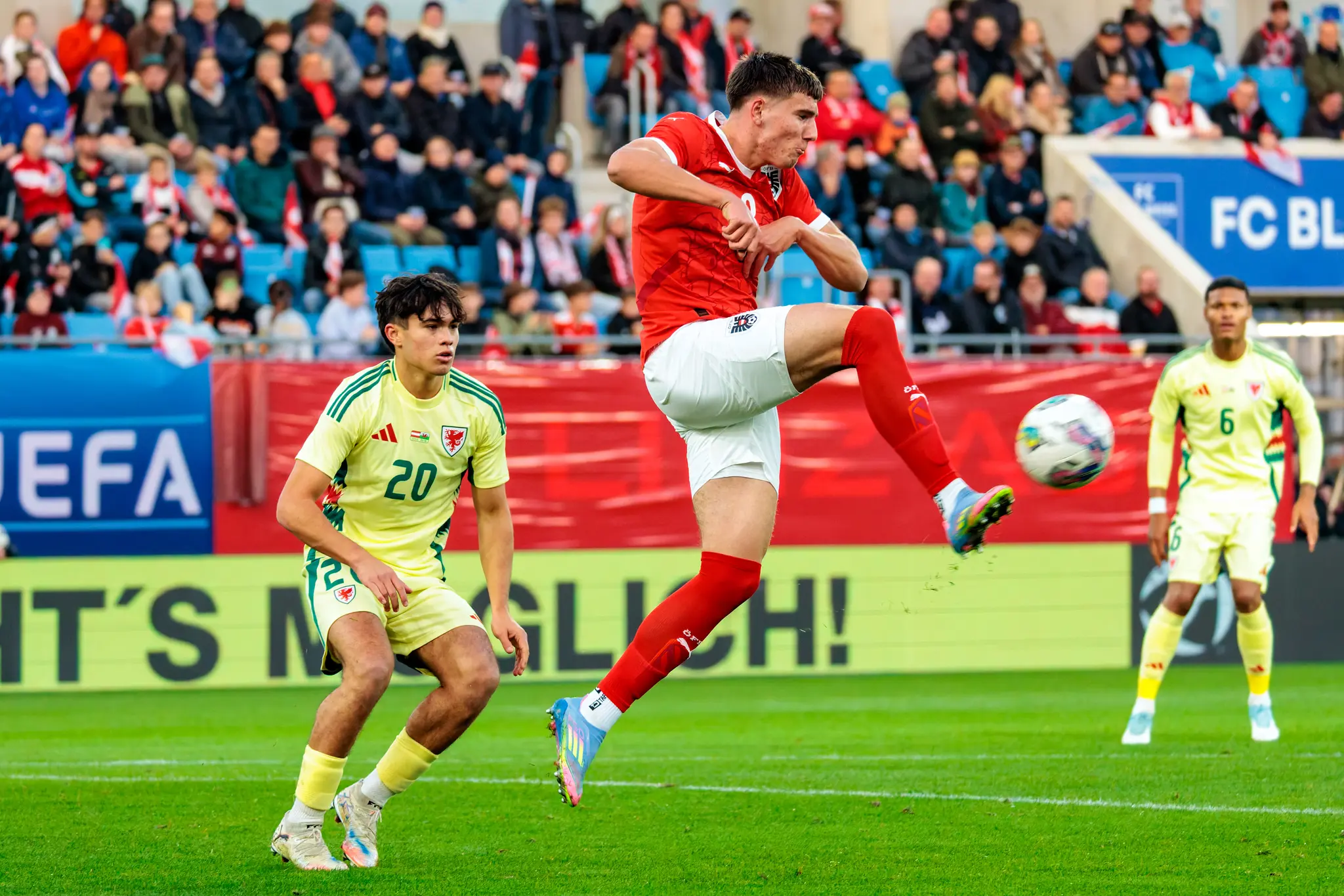 Der österreichische U21-Spieler David Piczka schießt den Ball in einem dynamischen Sprung, während der walisische Gegenspieler Gabriele Biancheri die Aktion beobachtet