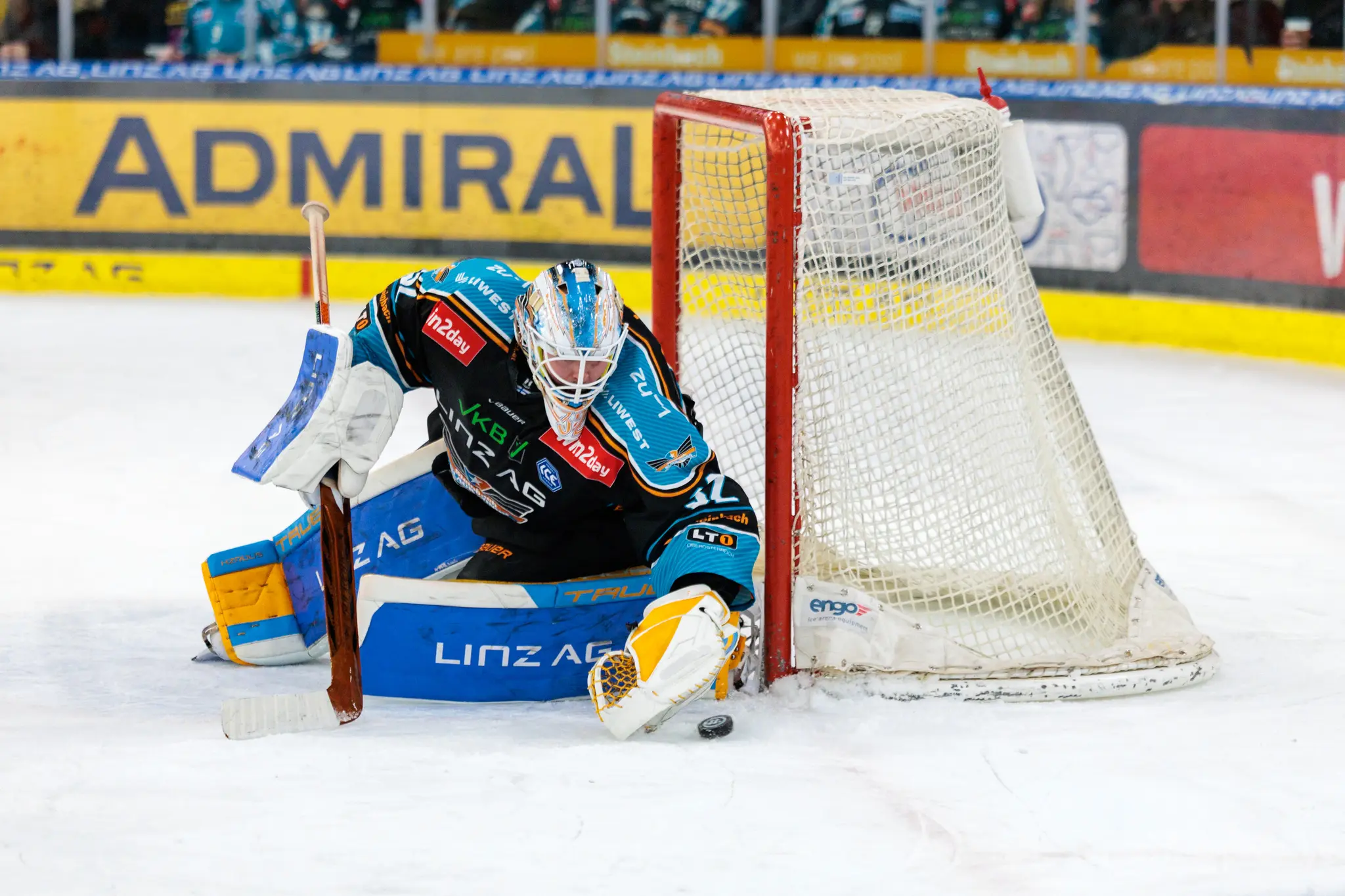 Eishockey-Goalieder Black Wings Linz  wehrt einen Puck vor dem Tor auf dem Eis ab 