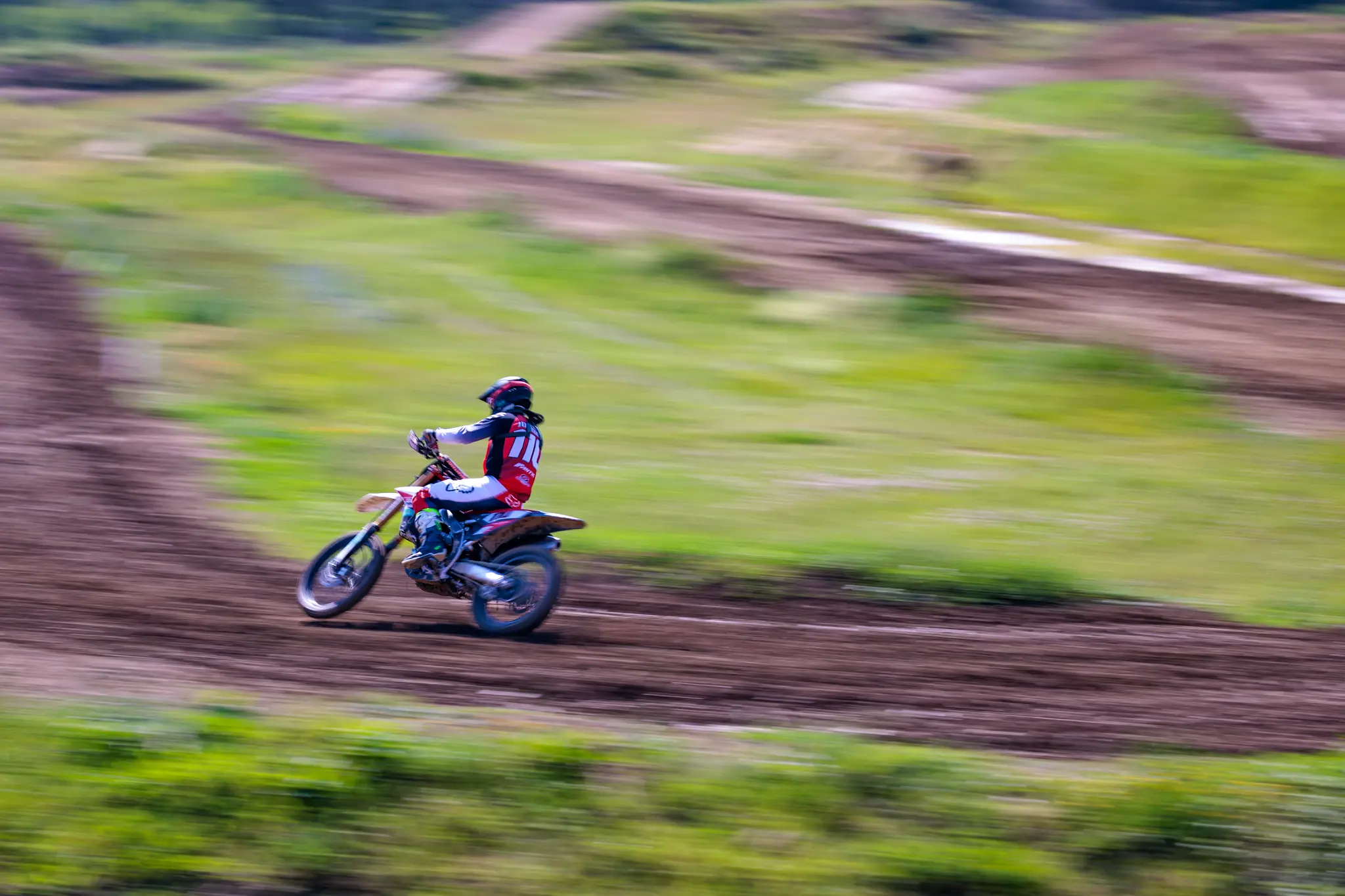 Mitzieher eines Motocross-Fahrer auf Dirtbike in schneller Fahrt bei Motorsport-Event 